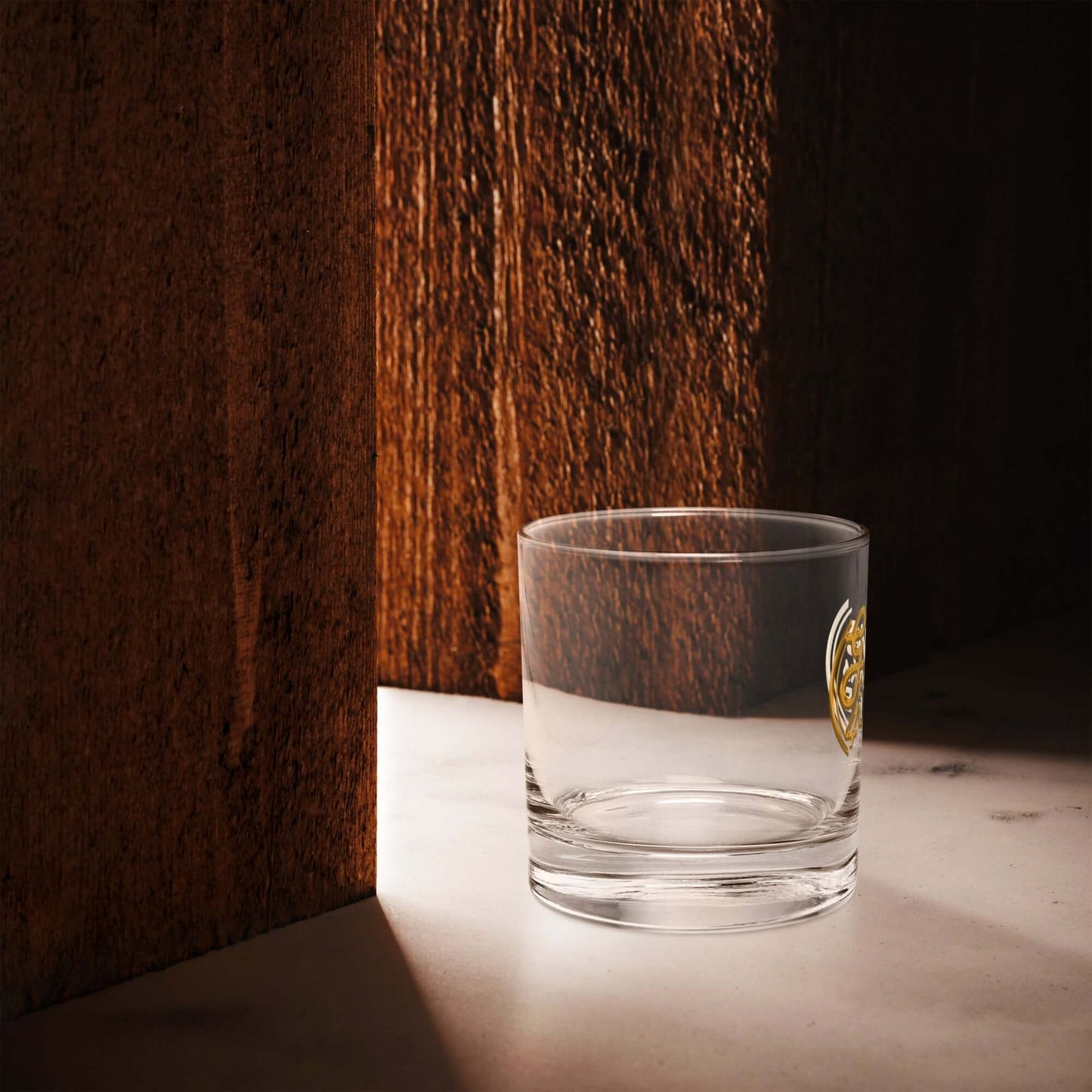 Clear glass with a gold emblem on a wooden surface