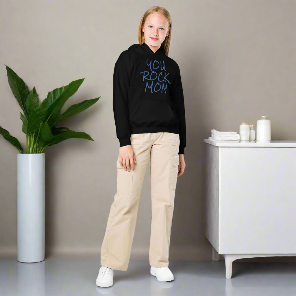 Person wearing a black hoodie with 'YOU ROCK MOM' text, beige pants, and white shoes on a white background