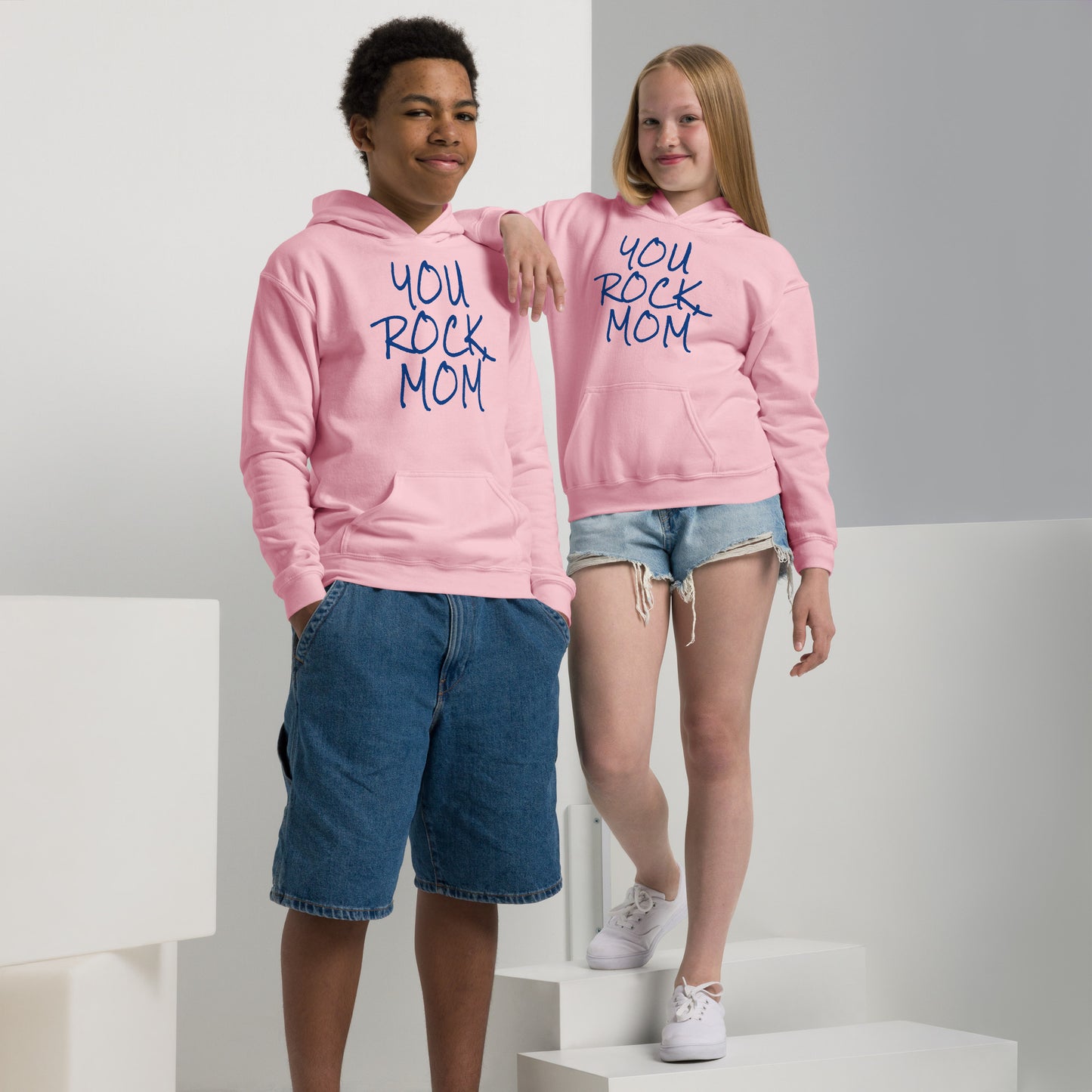 Two children wearing pink hoodies with 'You Rock Mom' text, standing on a white platform.