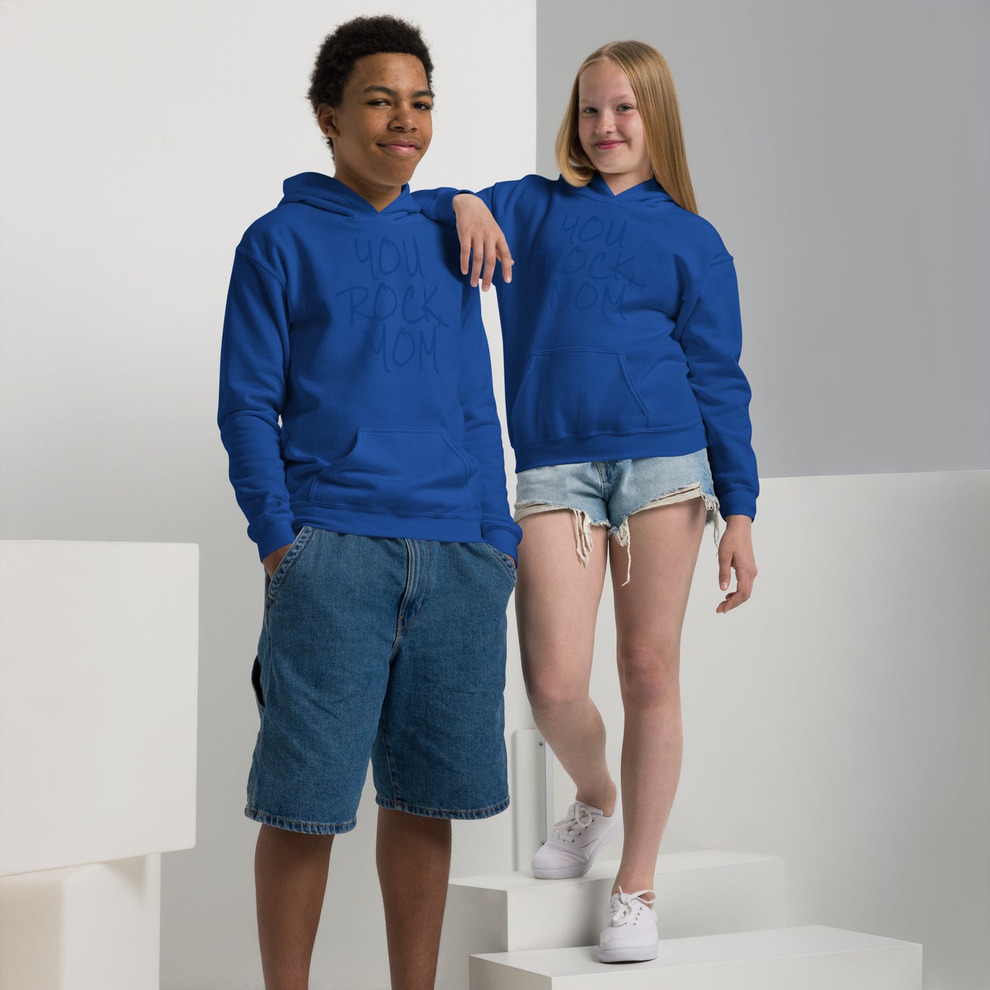 Two children wearing blue hoodies with 'You Rock' text, standing on a white platform.
