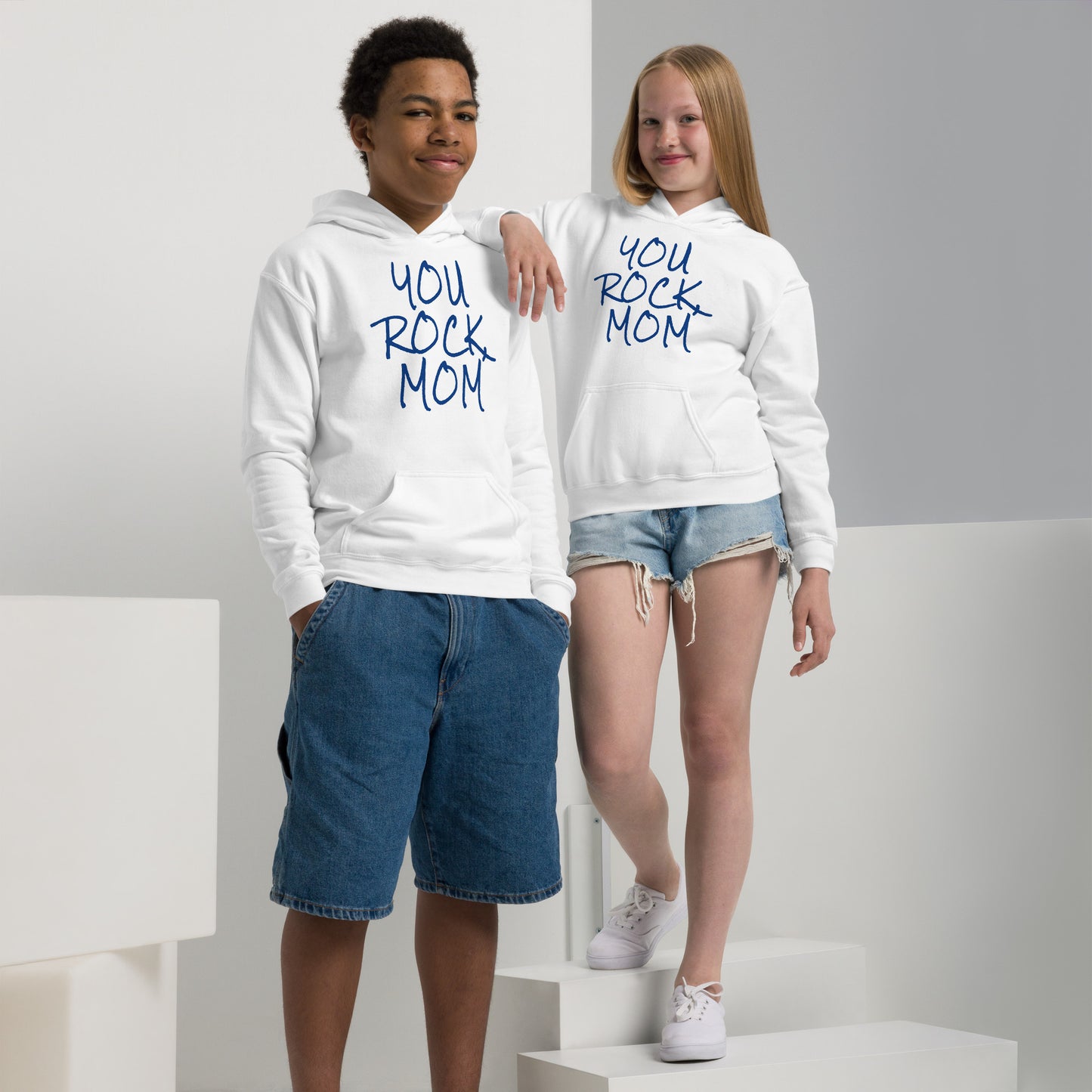 Two children wearing white hoodies with 'YOU ROCK MOM' text on a plain background
