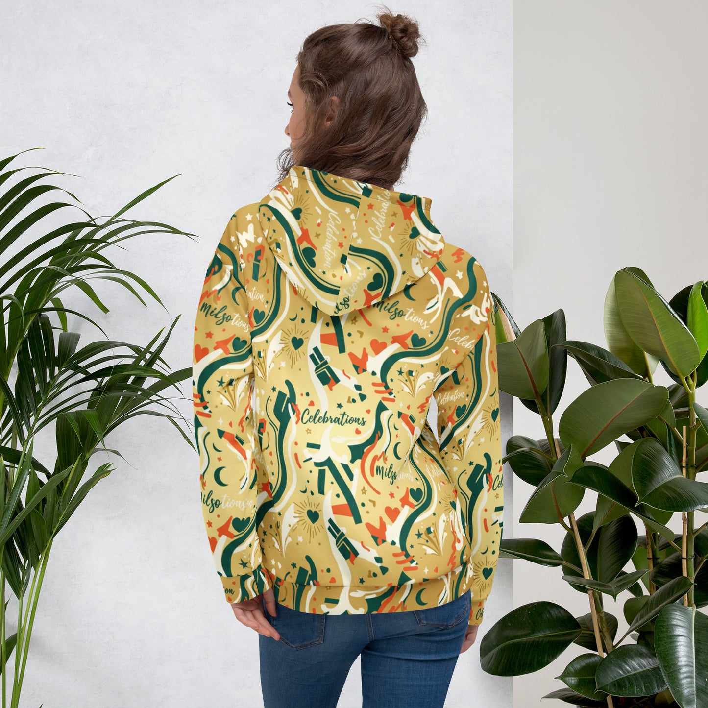 Person wearing a colorful hoodie with abstract design, standing between two potted plants.