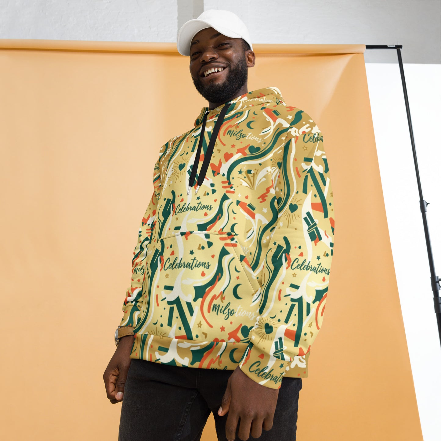 Man wearing a colorful hoodie with patterns and text, standing against an orange background