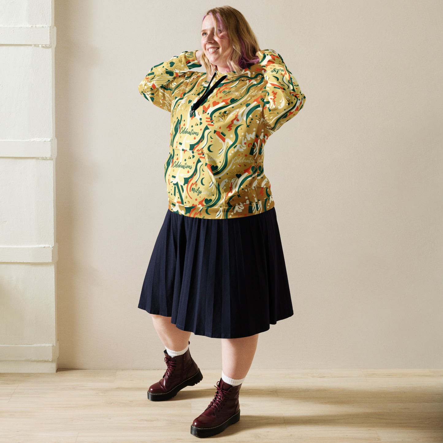 Person wearing a colorful patterned shirt and dark skirt standing against a plain wall.
