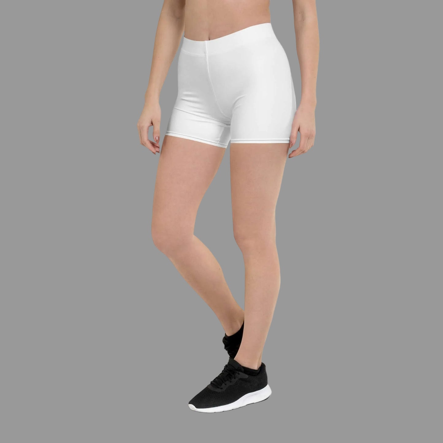 Person wearing white athletic shorts and black sneakers on a white background