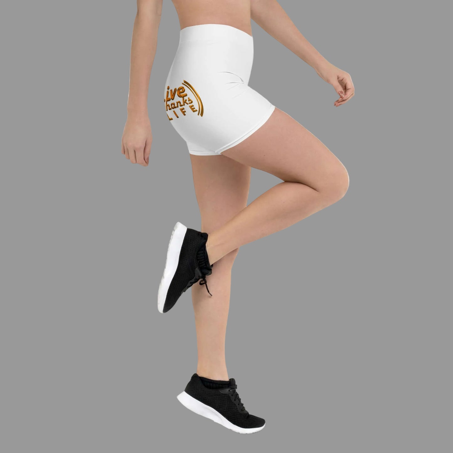 Person wearing white shorts with a gold logo and black sneakers on a white background