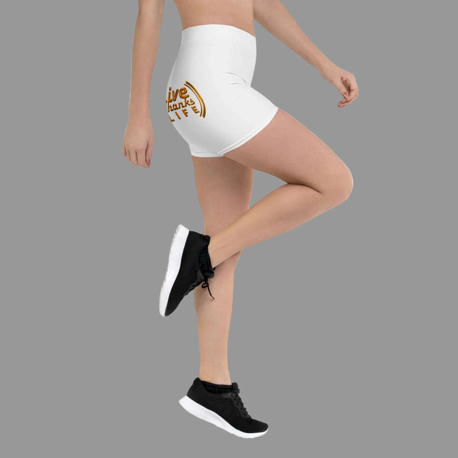 Person wearing white shorts with a gold logo and black sneakers on a white background