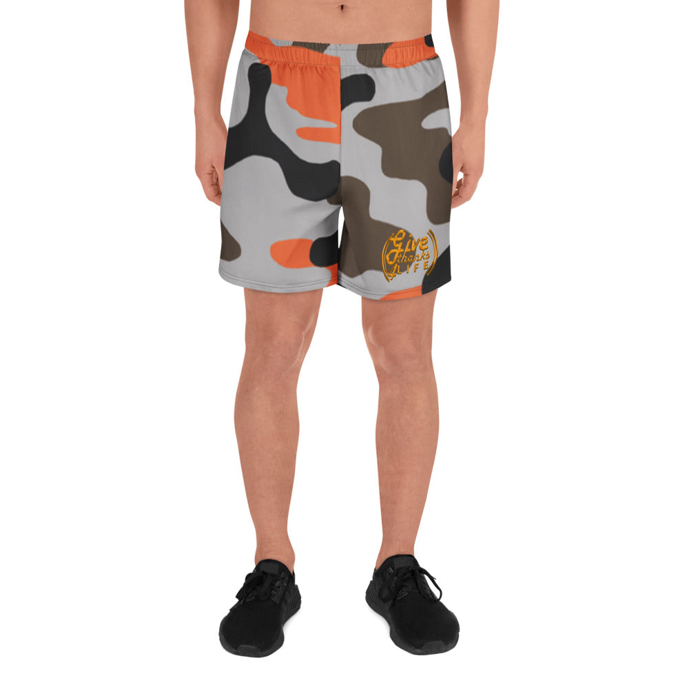 Camouflage shorts with orange accents worn by a person on a white background