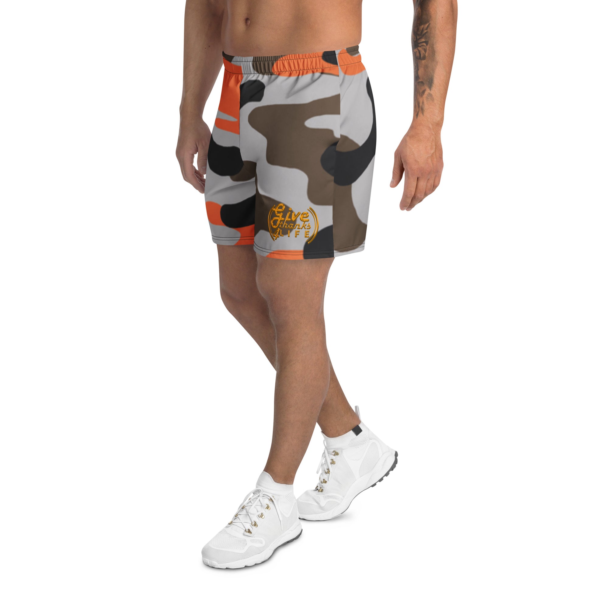 Camouflage shorts with orange accents worn by a person on a white background