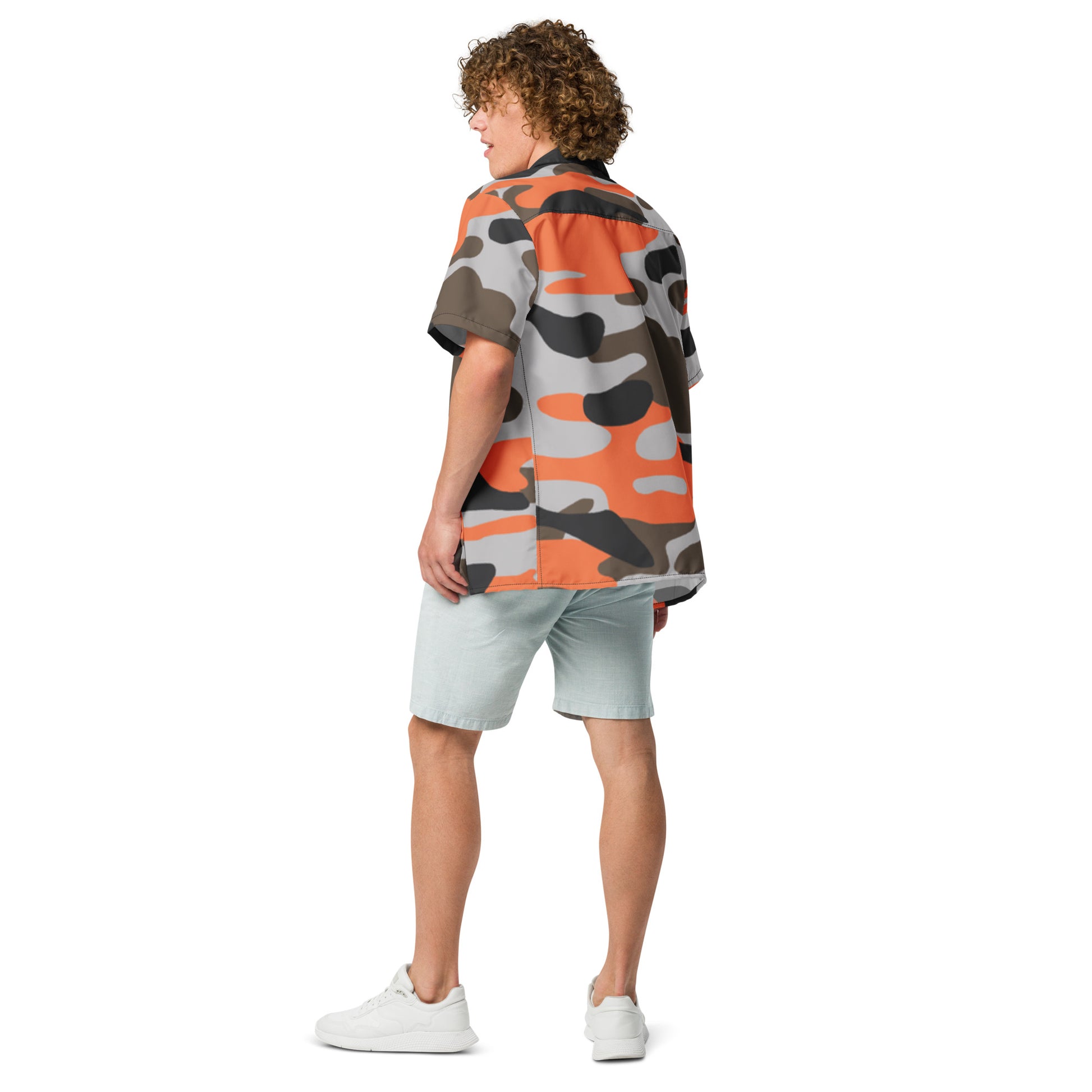Person wearing a colorful camouflage shirt and light shorts on a white background