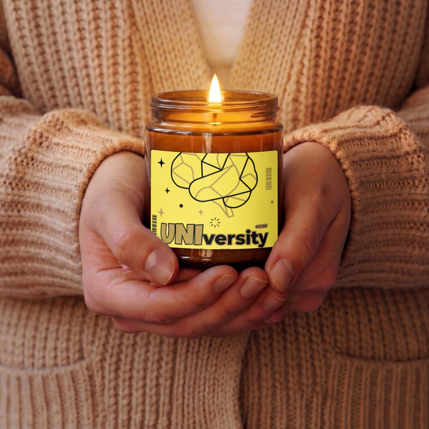 Person holding a lit candle with a 'UNIversity' label in a warm setting