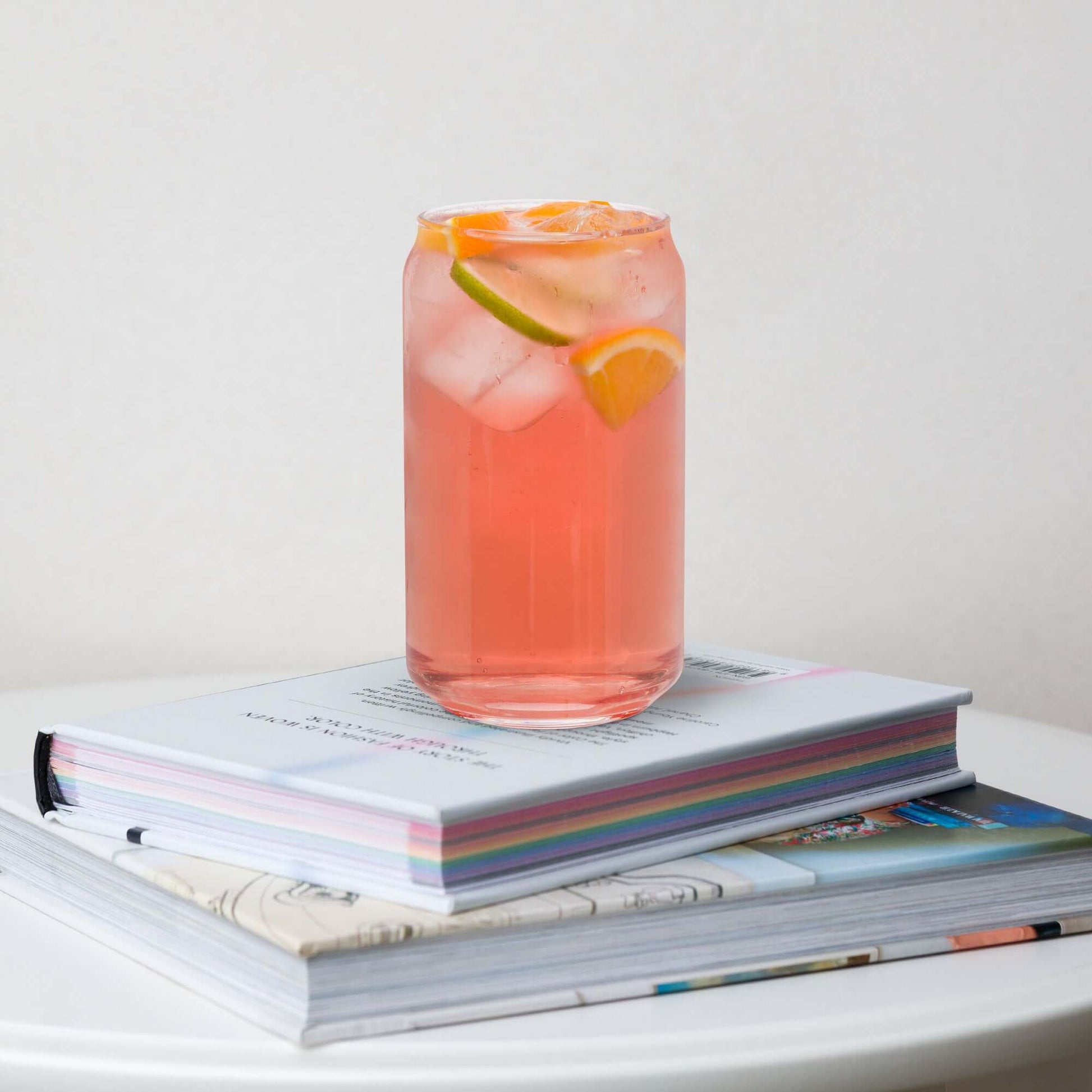 Glass of pink lemonade with ice and lemon slices on a stack of books