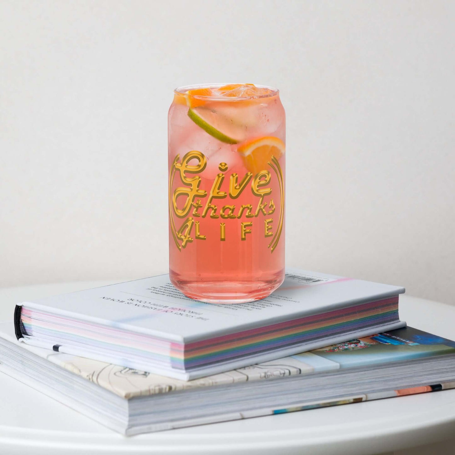 Pink glass with 'Give Thank Life' text on a stack of books