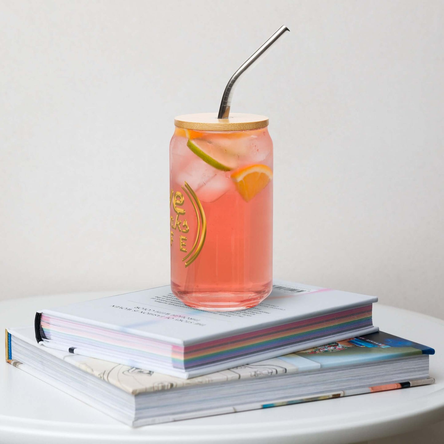 Pink lemonade in a can with a straw on top of books
