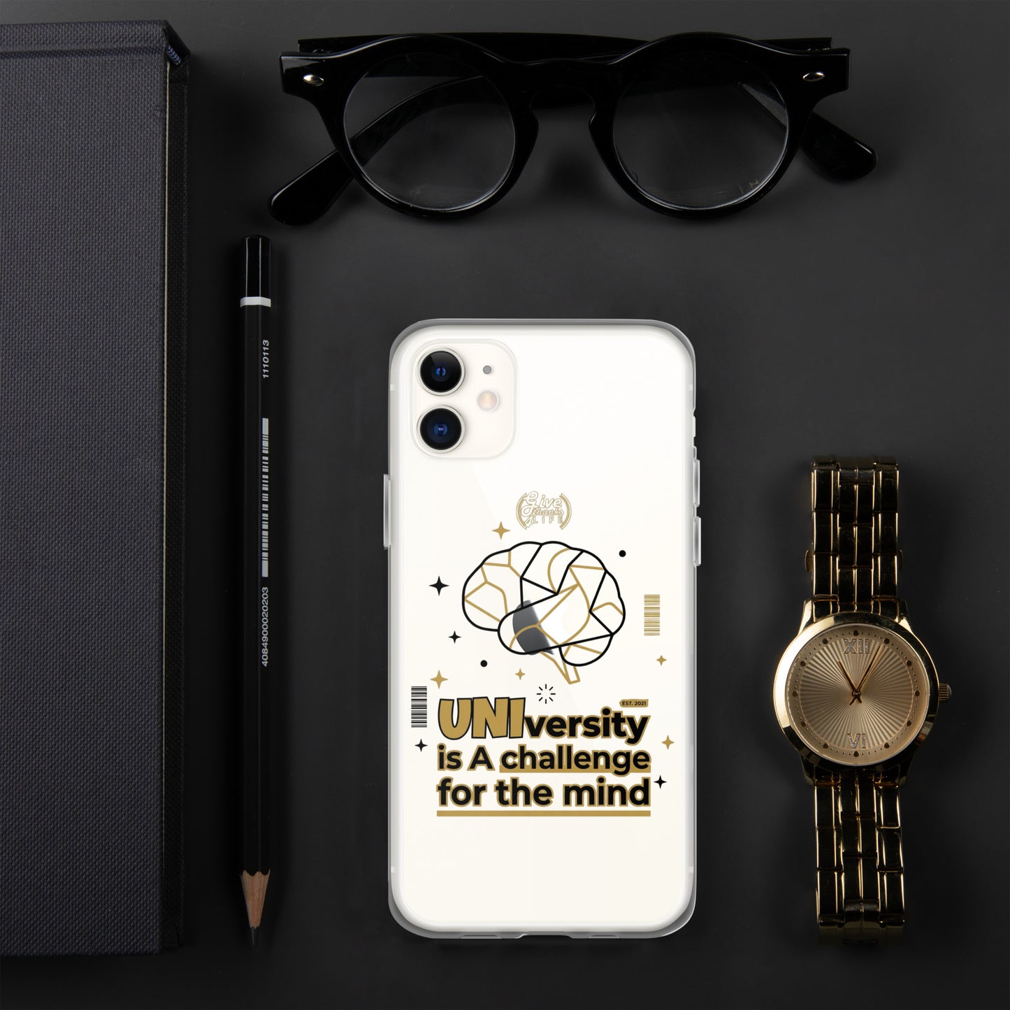 Phone case with 'UNI'versity is a challenge for the mind design on a dark surface with glasses, pen, and watch.