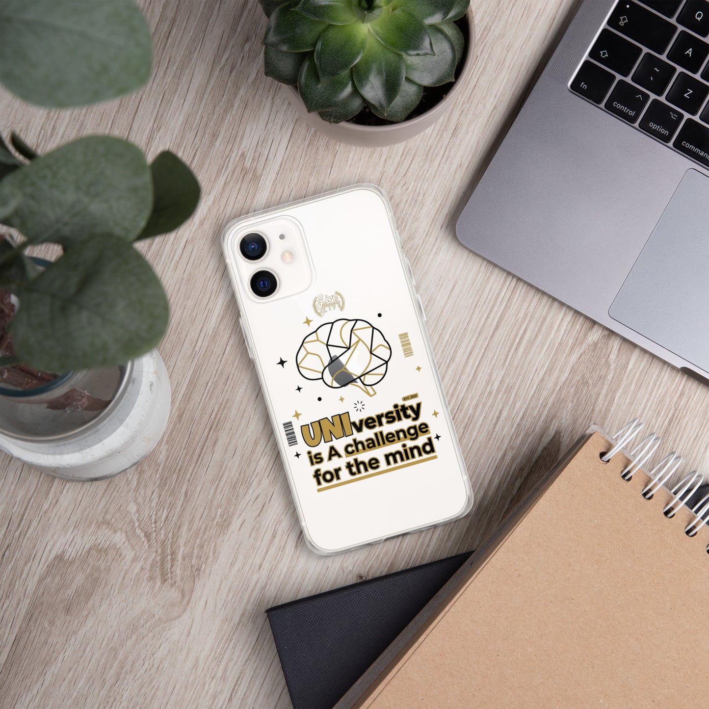 Phone case with 'University is a challenge for the mind' text on a desk with laptop and plants