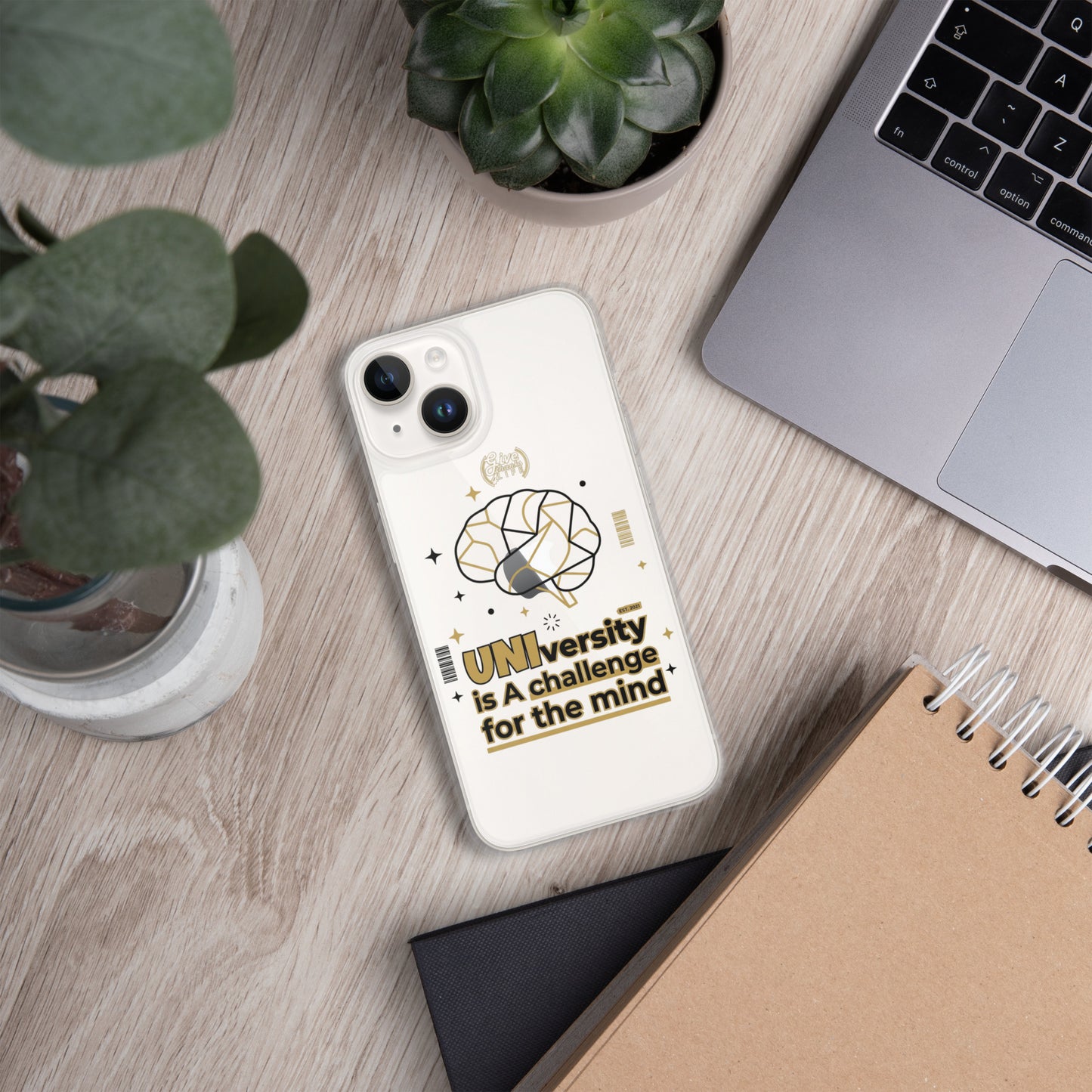 Phone case with 'UNI'versity is a challenge for the mind design on a wooden surface with a laptop and plant.