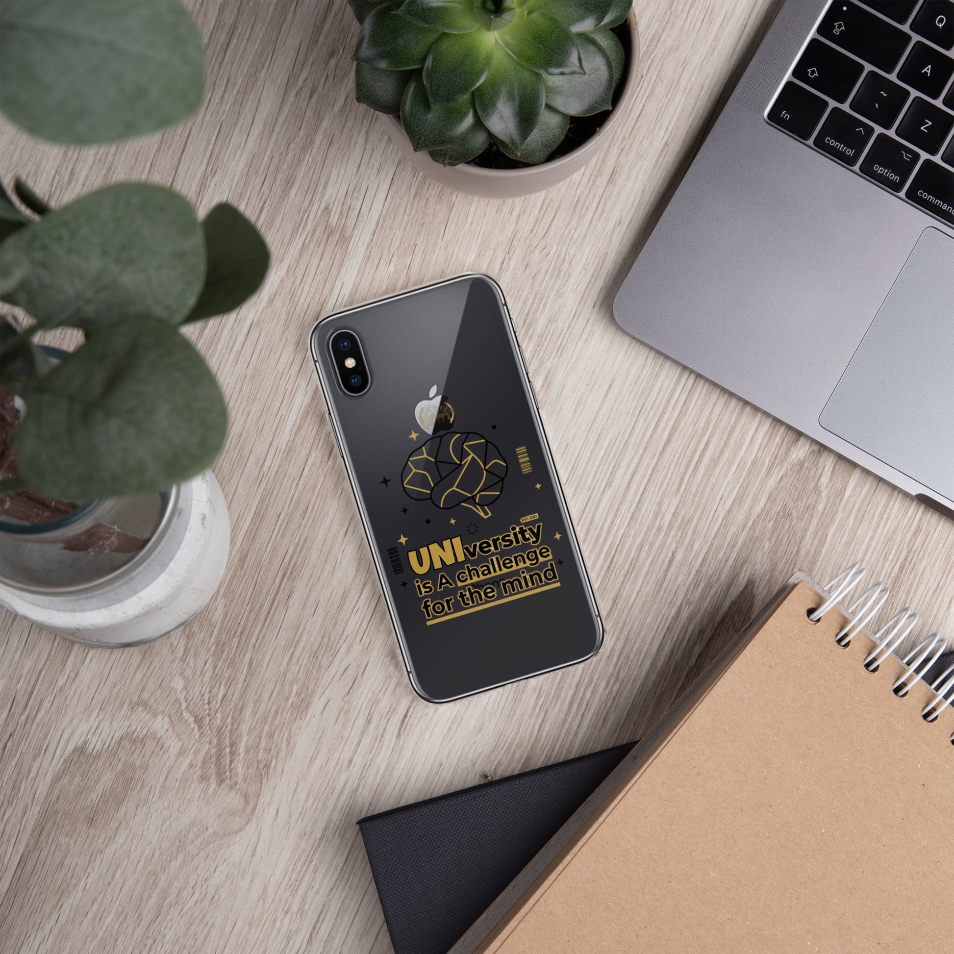 Phone case with text on a desk with laptop, notebook, and plants
