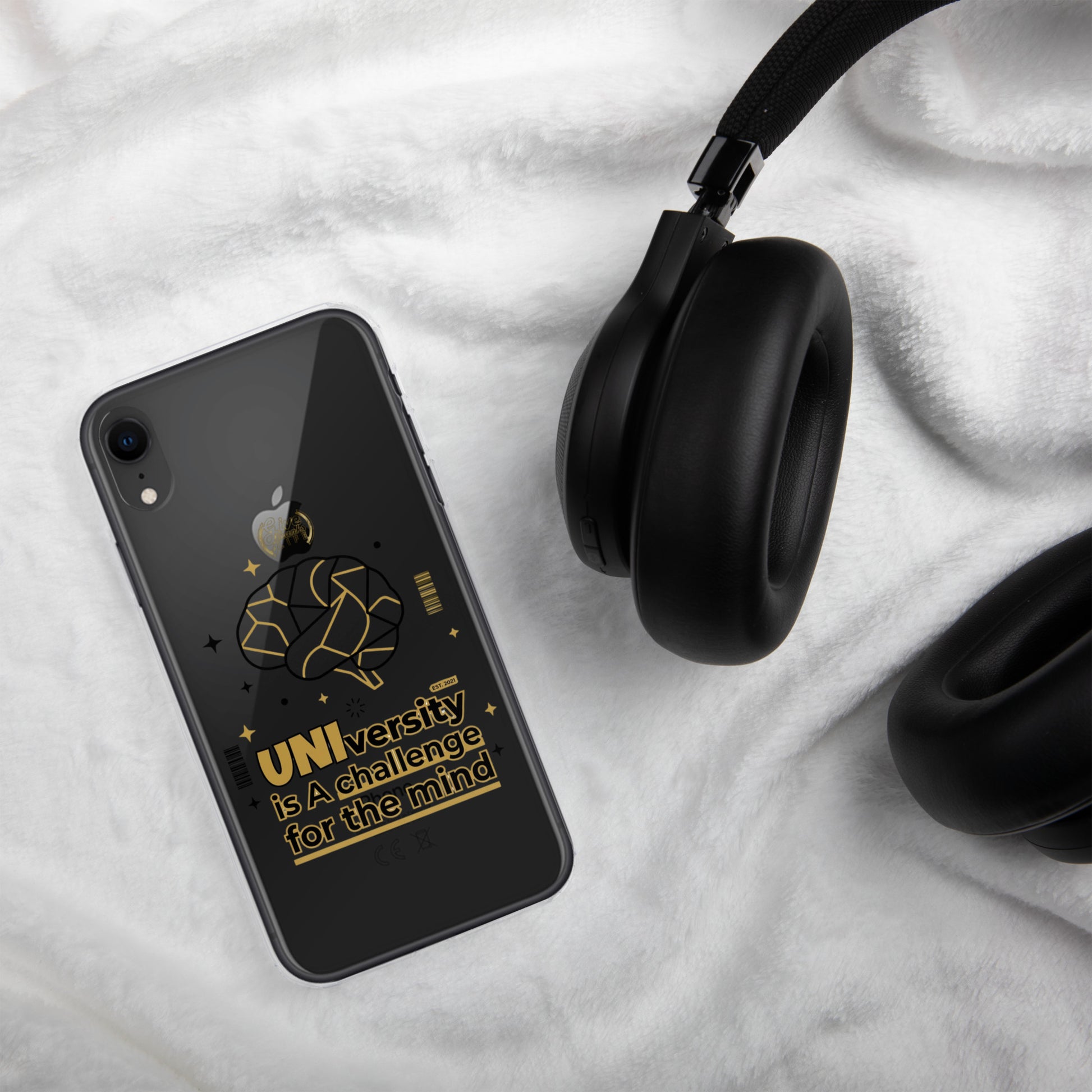Phone case with black flower design next to black headphones on a white fabric background