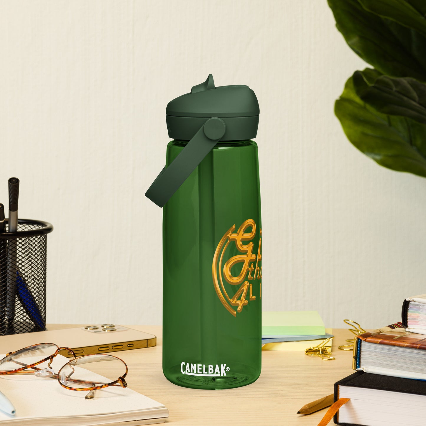 Green CamelBak water bottle on a desk with books and glasses