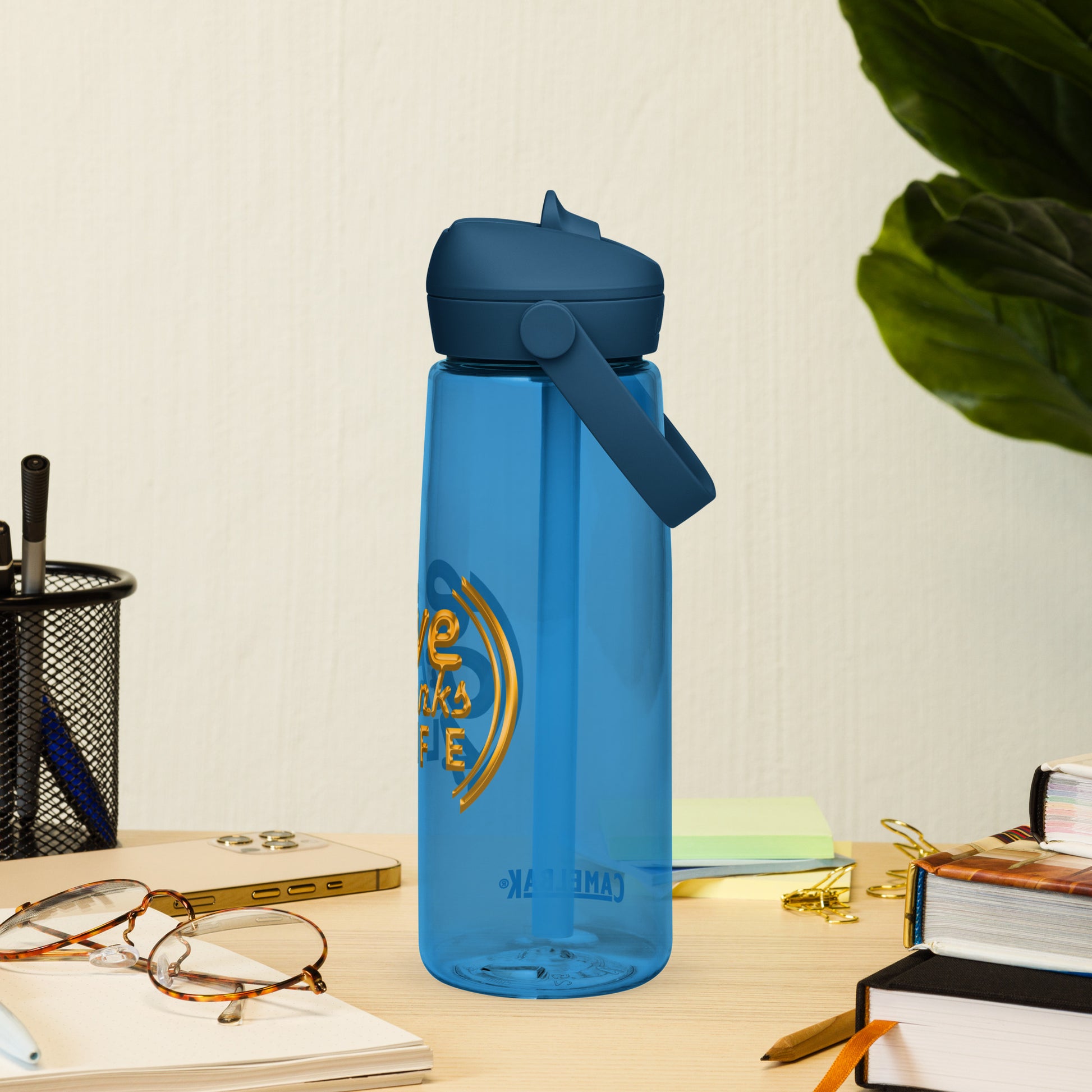 Blue water bottle with a logo on a desk with books and glasses