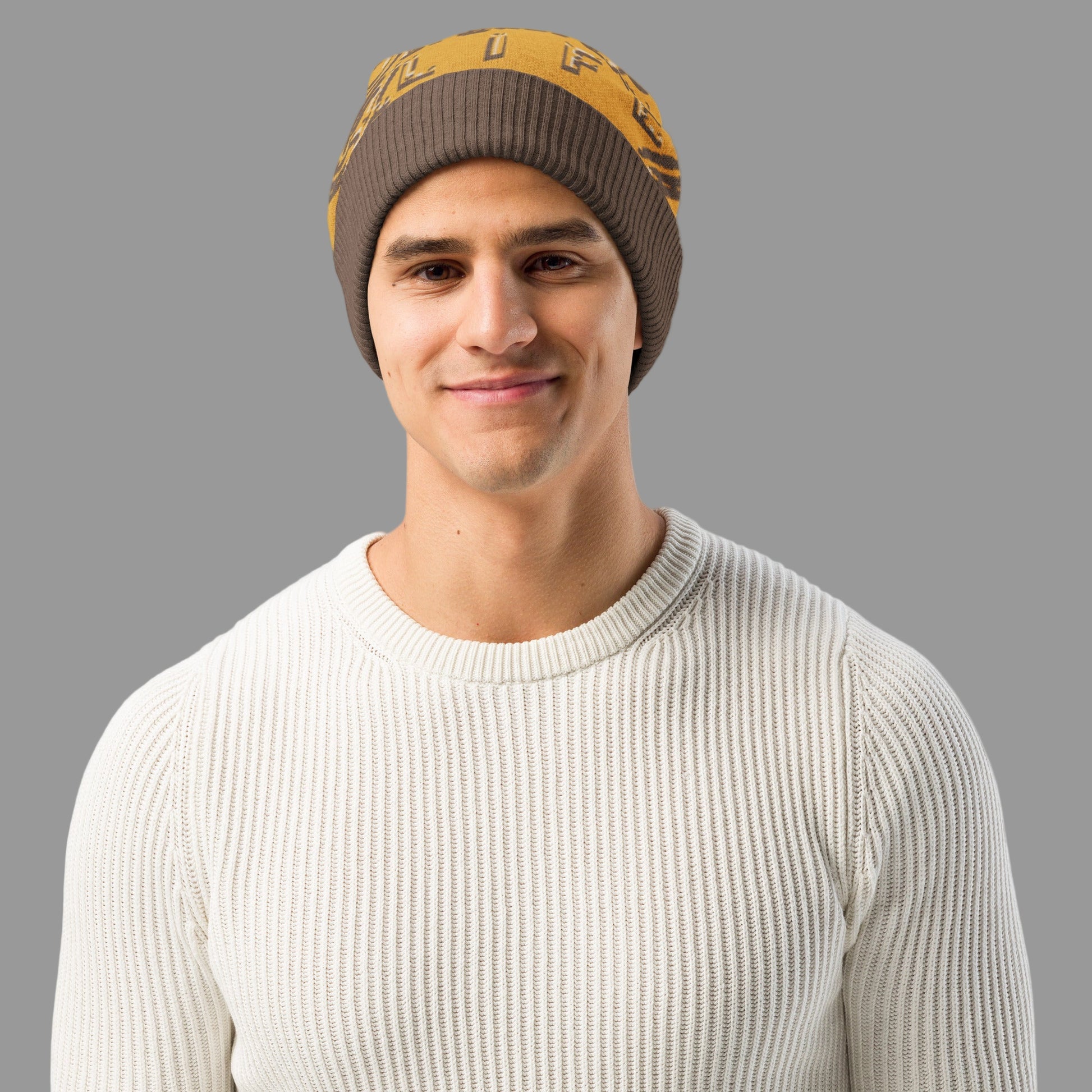 Man wearing a brown and yellow beanie with a white sweater on a white background