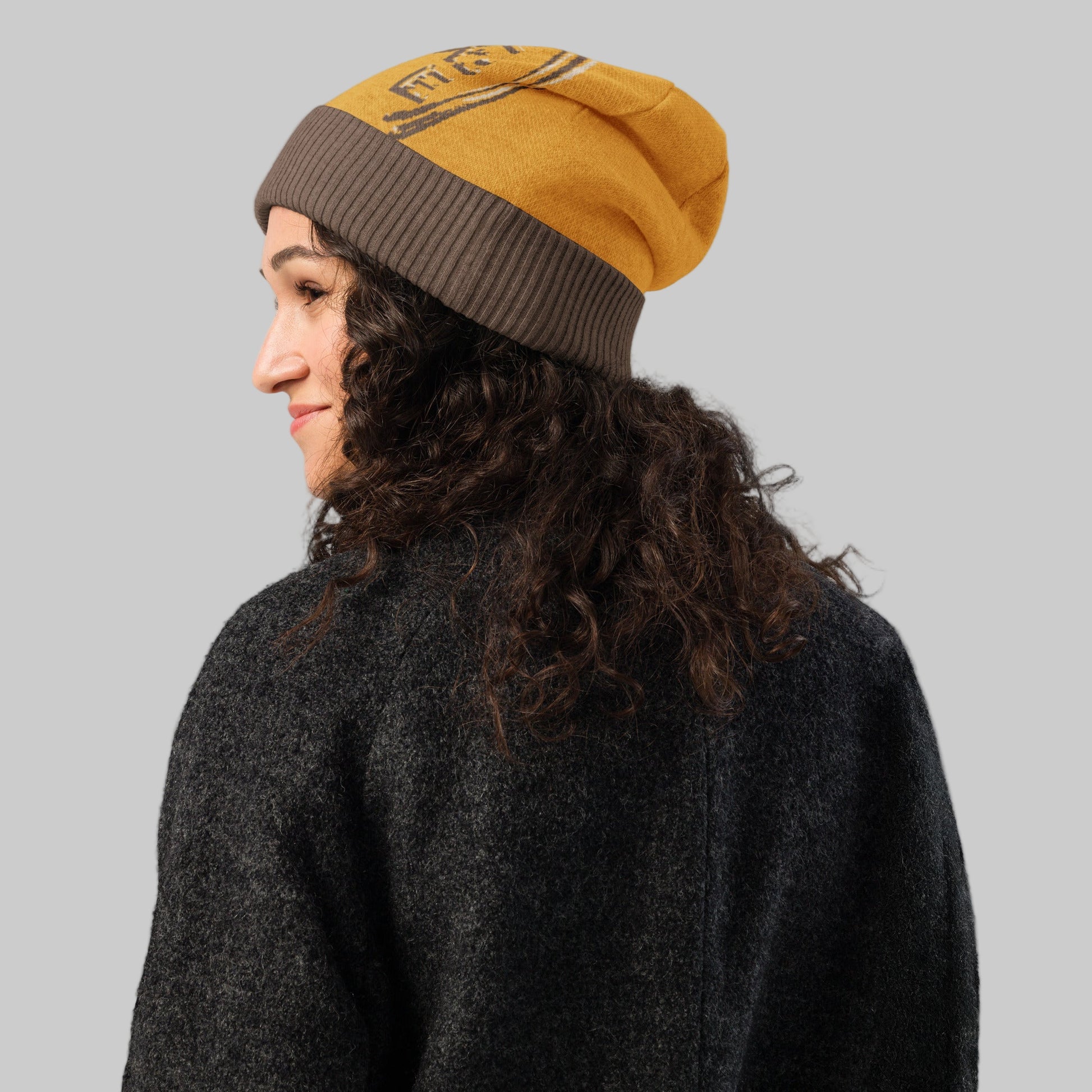 Person wearing a yellow and brown beanie on a white background