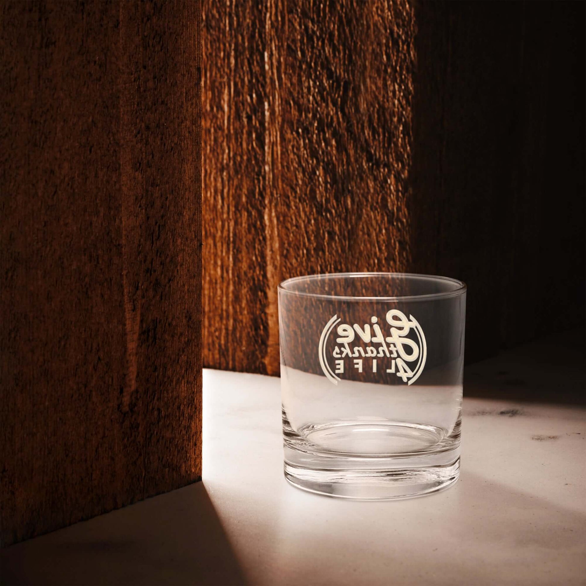 Clear glass with engraved text on a wooden surface