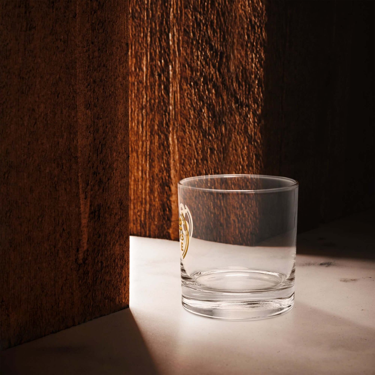 Clear glass with a gold emblem on a wooden surface