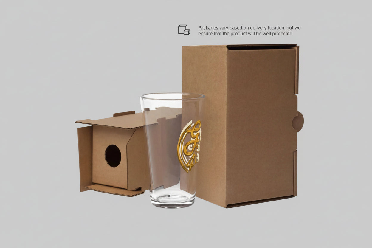 Clear glass with gold design next to a cardboard box on a white background