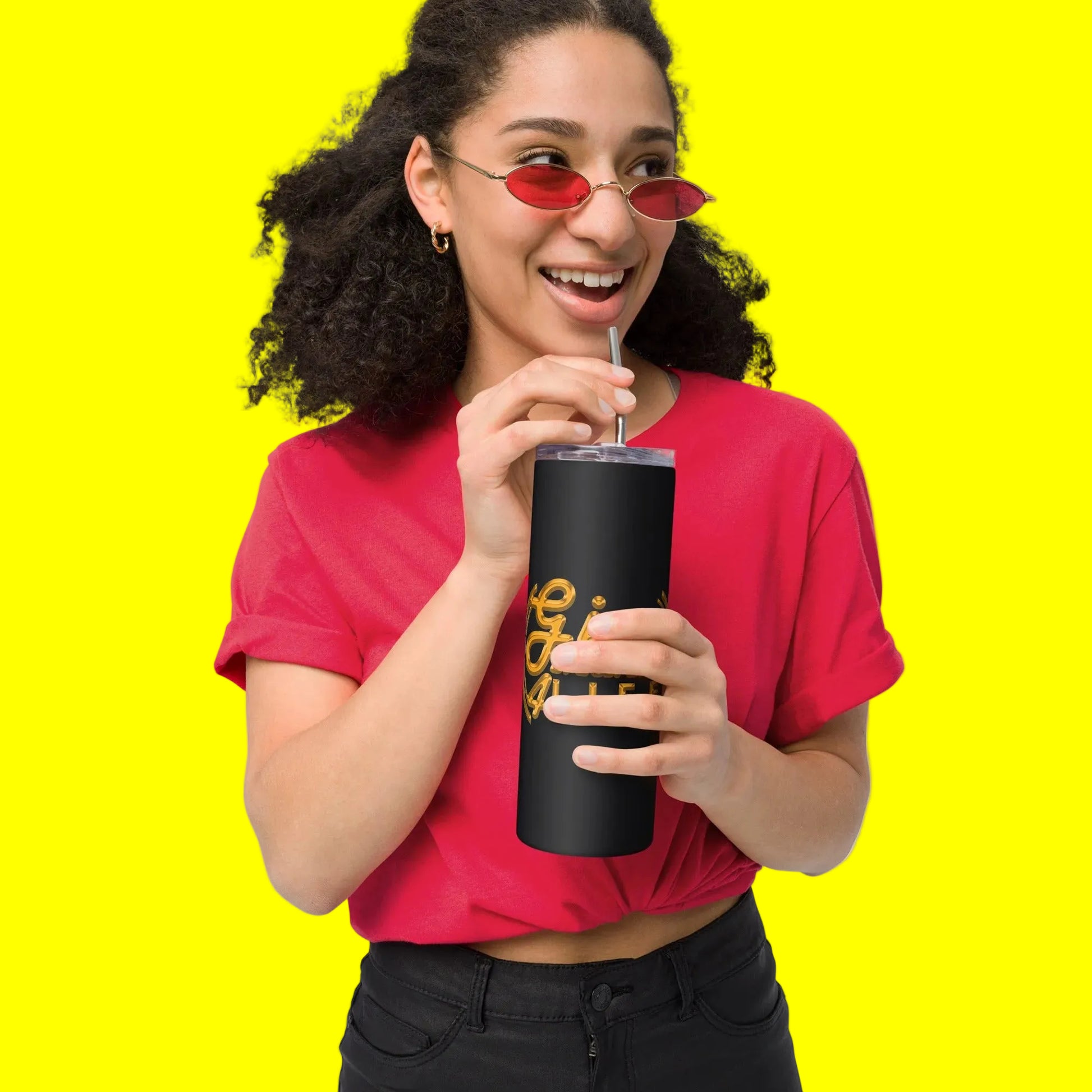 Person wearing a red shirt and sunglasses, holding a black tumbler with a straw.