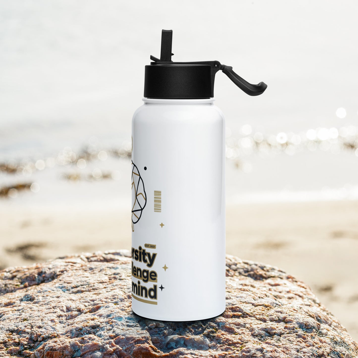 White water bottle with black cap on a rock by the beach