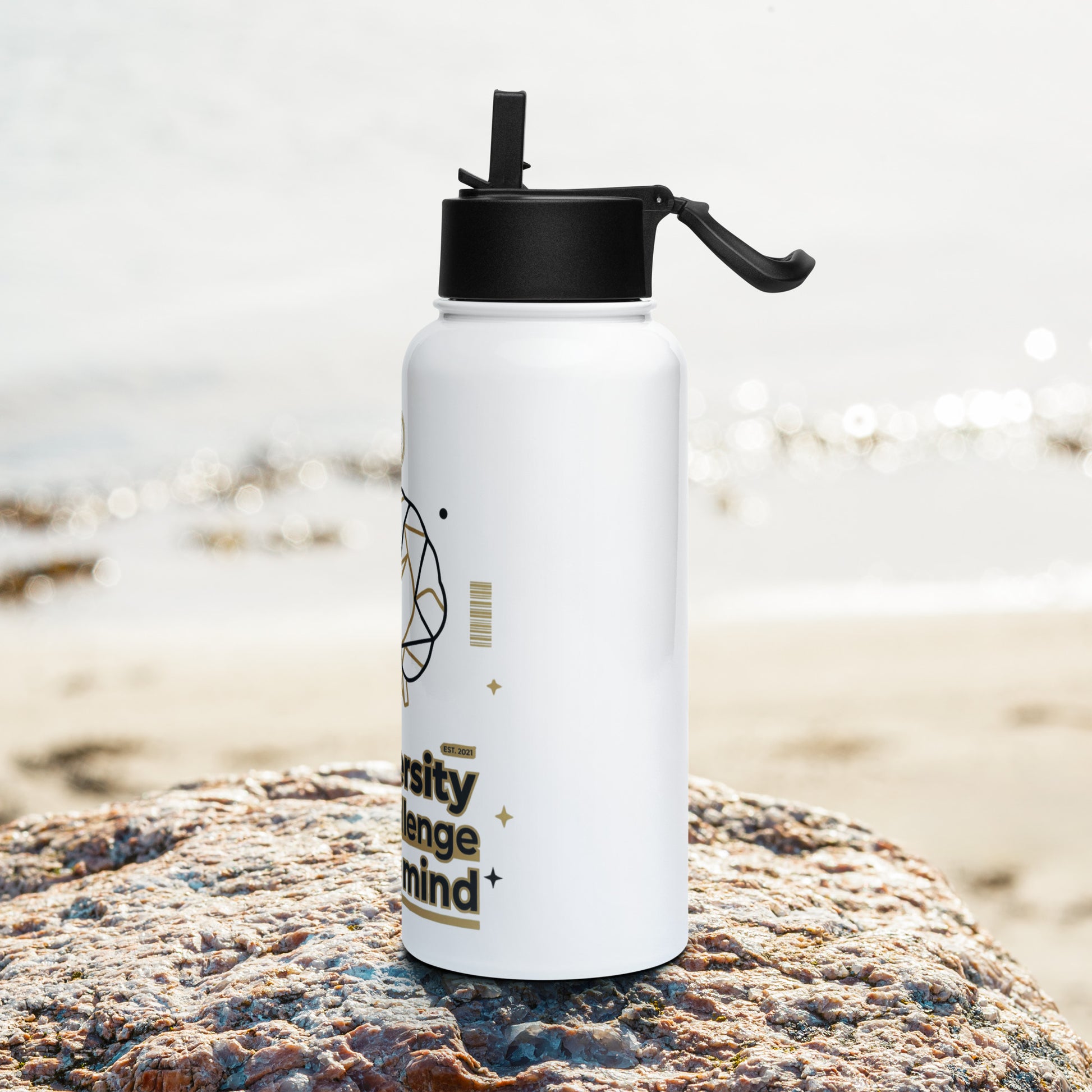 White water bottle with black cap on a rock by the beach