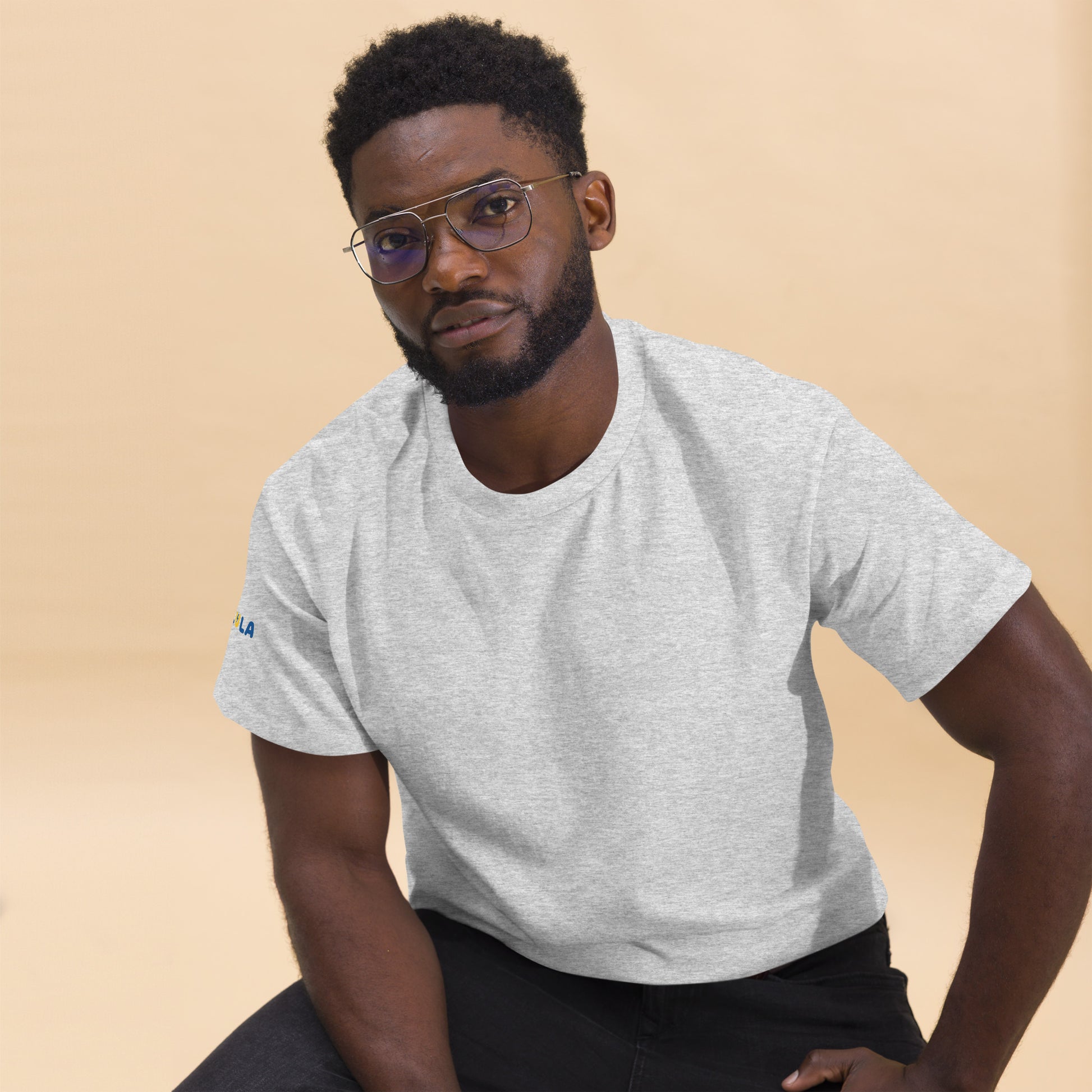 Man wearing a gray t-shirt with a logo on a beige background
