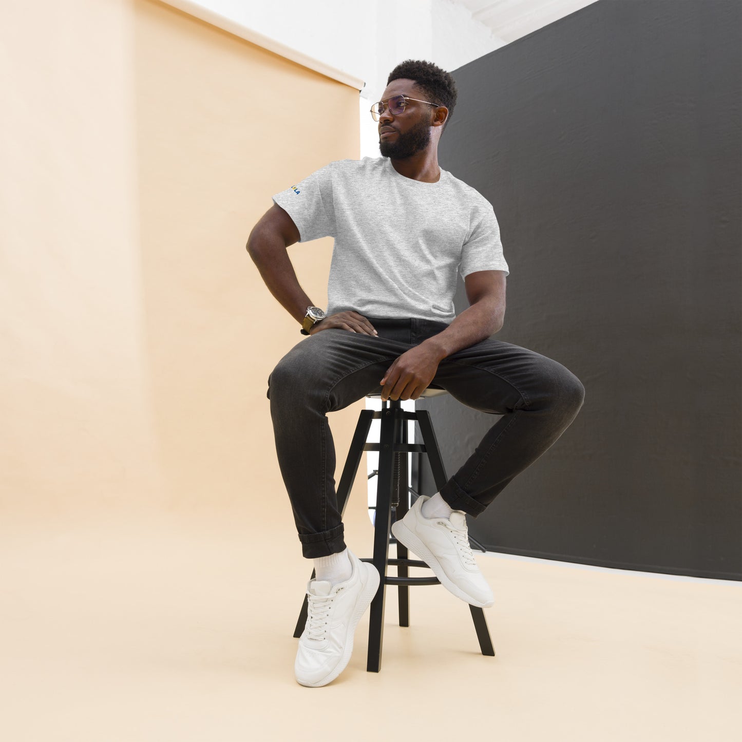 Man sitting on a stool against a plain background