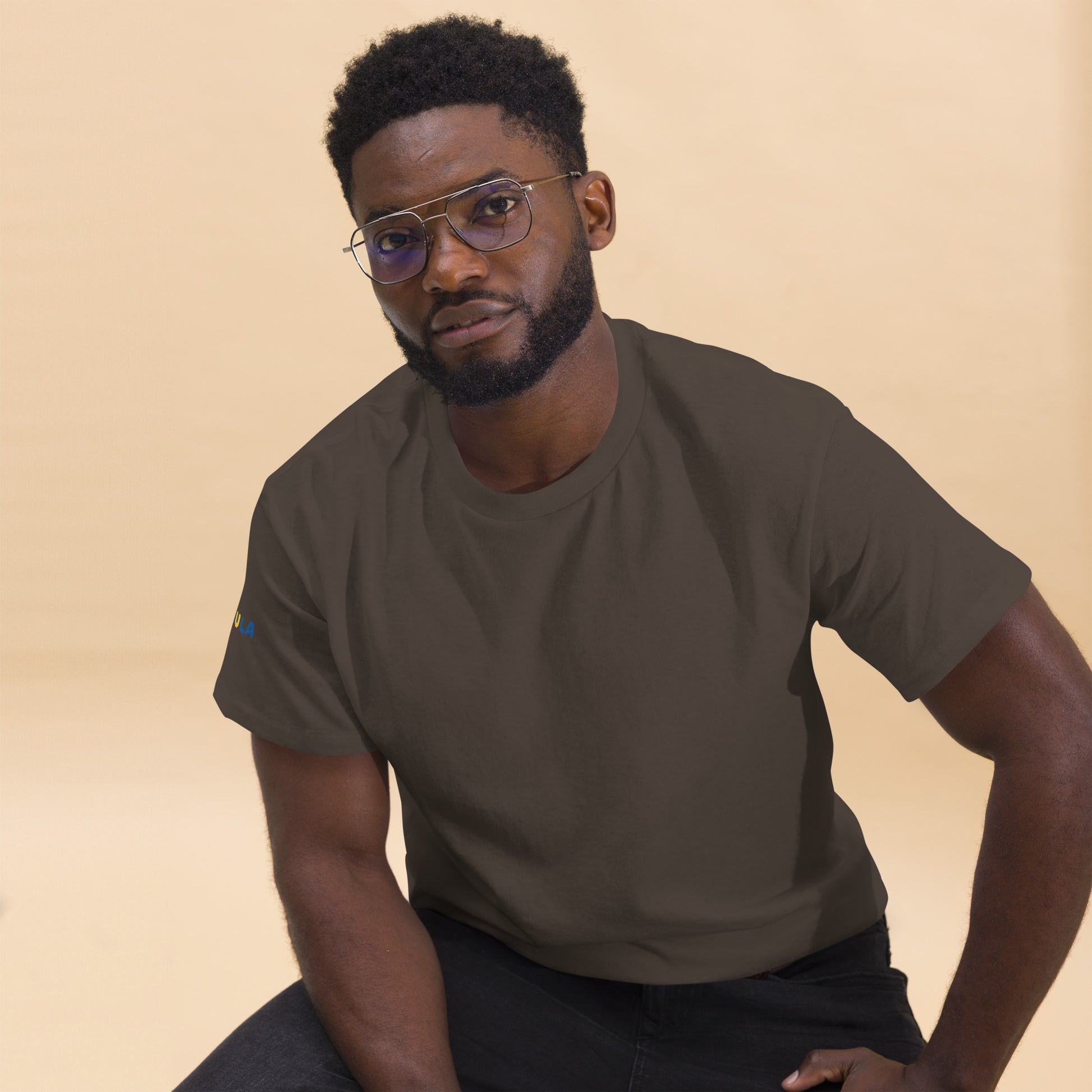 Man wearing a brown t-shirt against a beige background