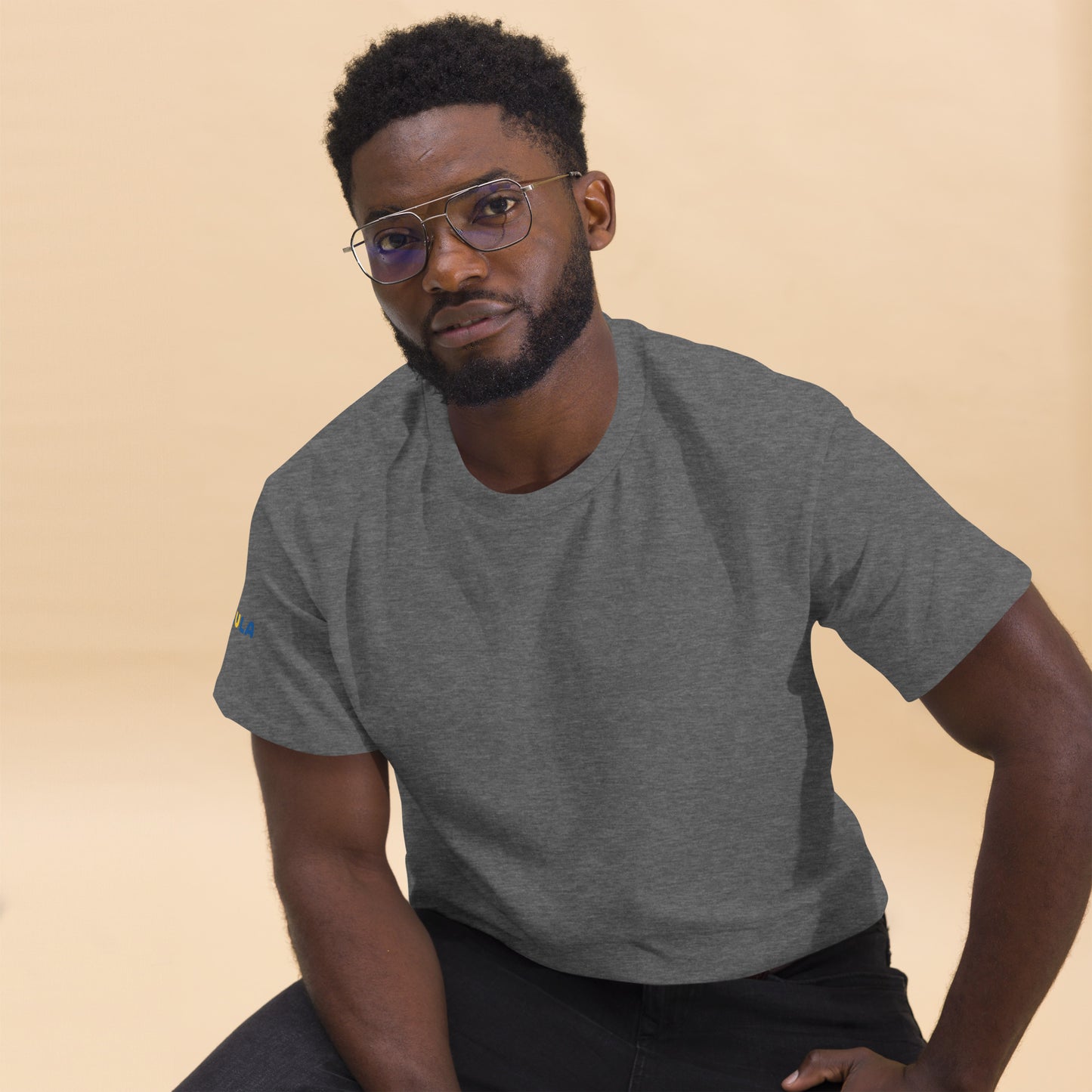 Man wearing a gray t-shirt with a logo on a beige background