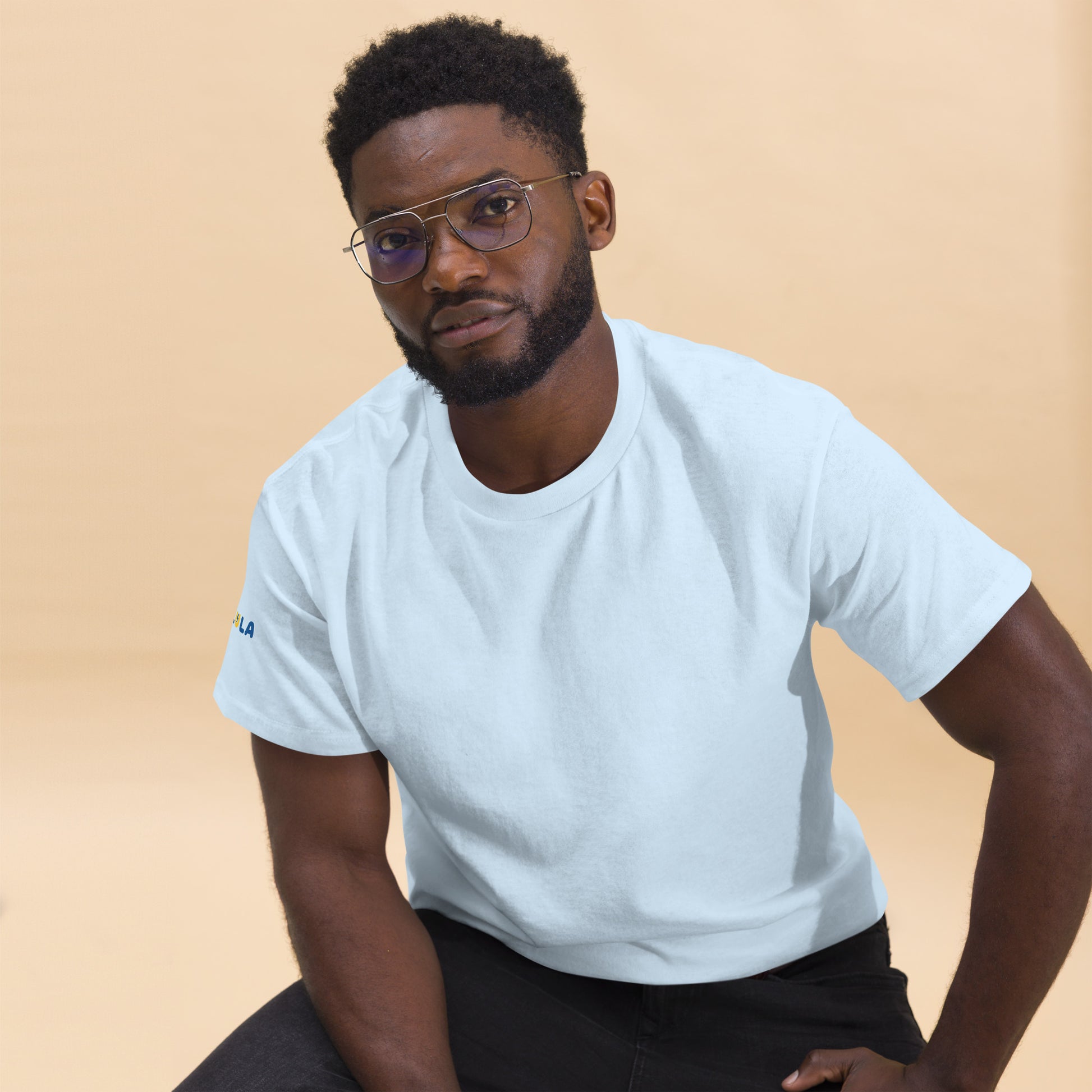 Man wearing a light blue t-shirt with a logo on a beige background
