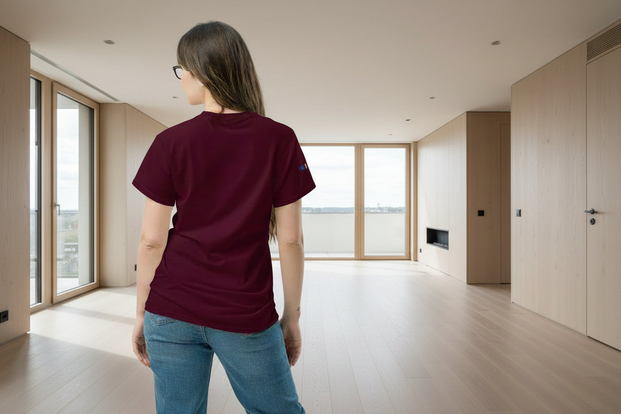 Person wearing a maroon t-shirt with a brand logo on the back, standing against a white background