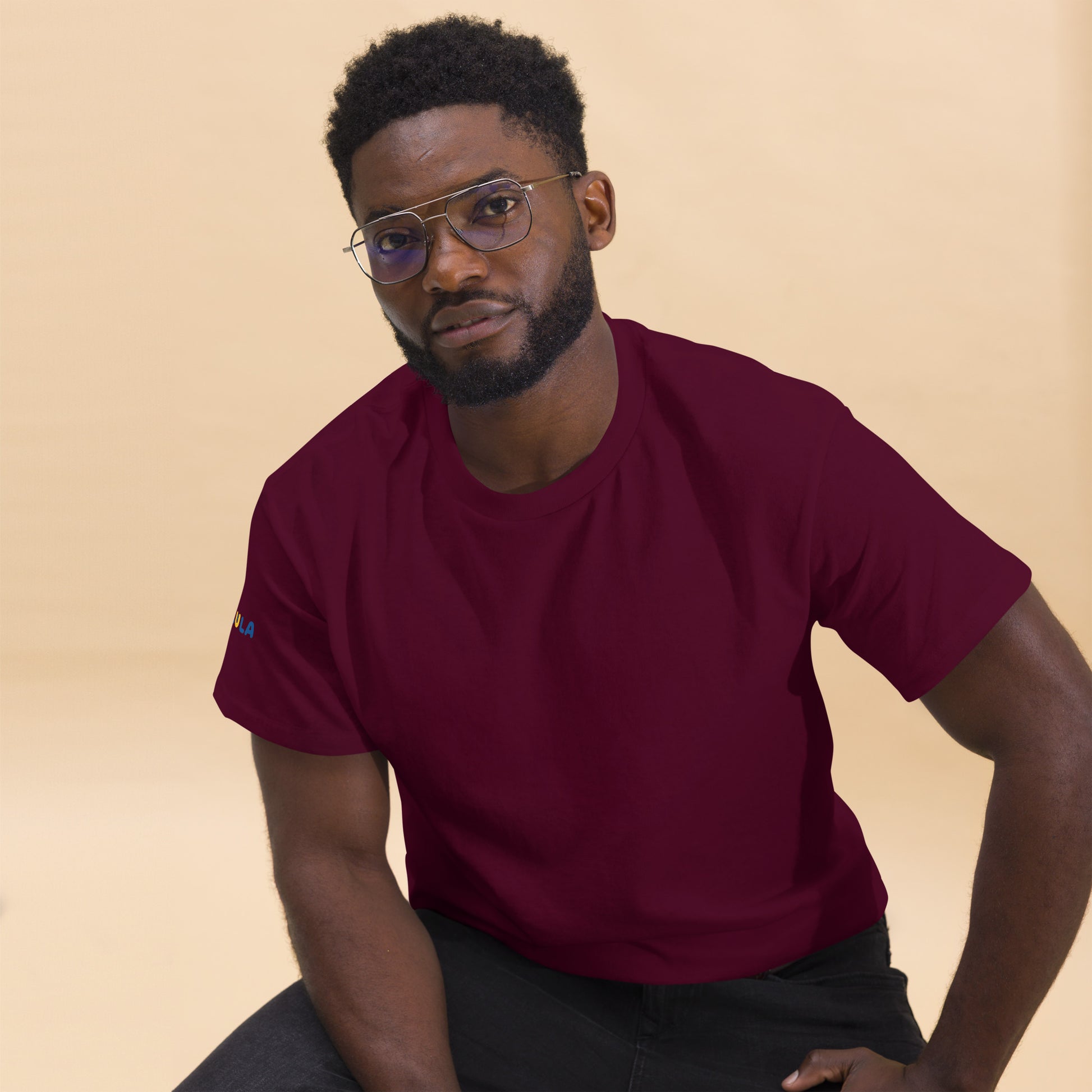 Man wearing a maroon t-shirt against a beige background