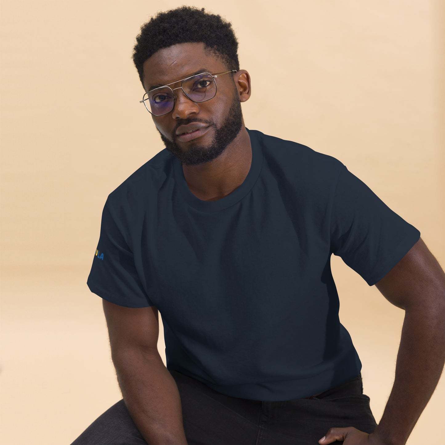 Man wearing a navy blue t-shirt against a beige background