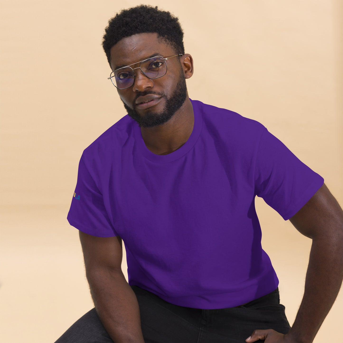 Man wearing a purple t-shirt against a beige background