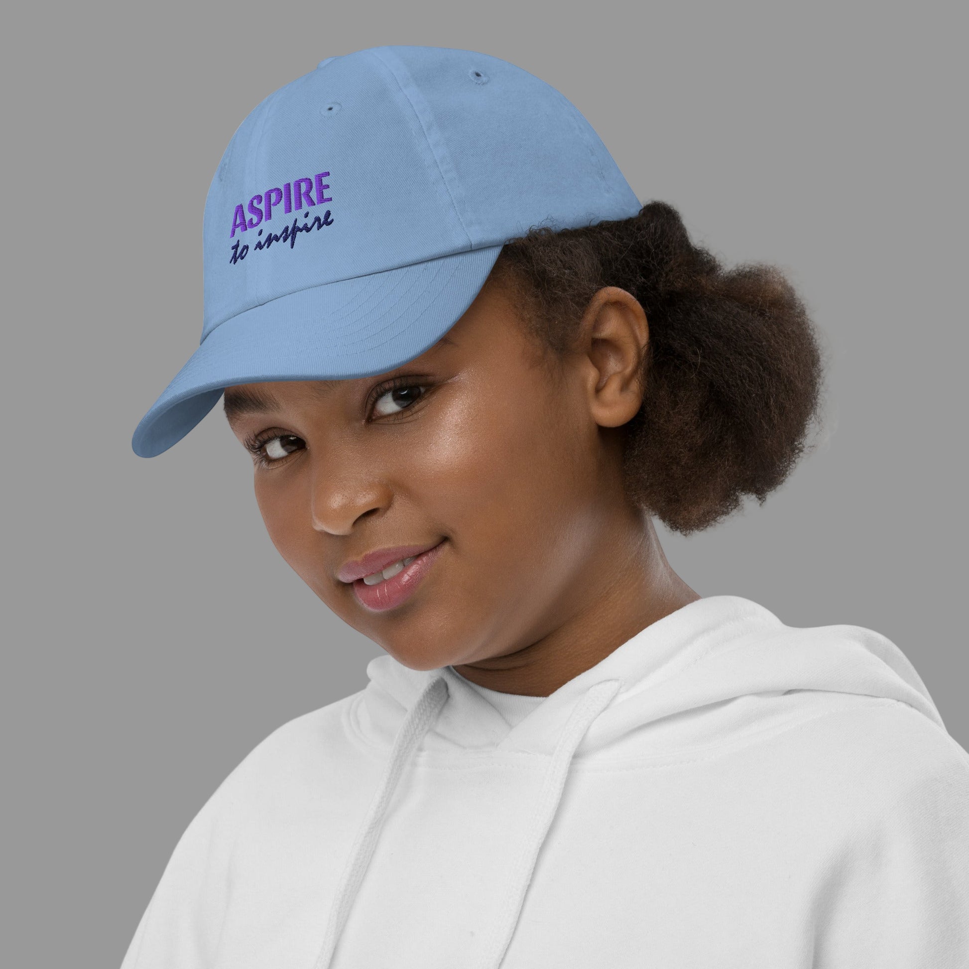Person wearing a blue cap with 'ASPIRE to inspire' text on a white background