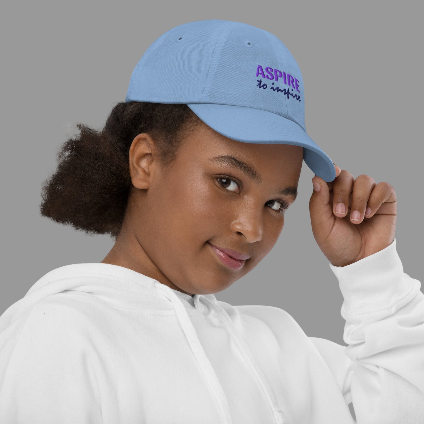 Person wearing a blue cap with 'ASPIRE to inspire' text on a white background