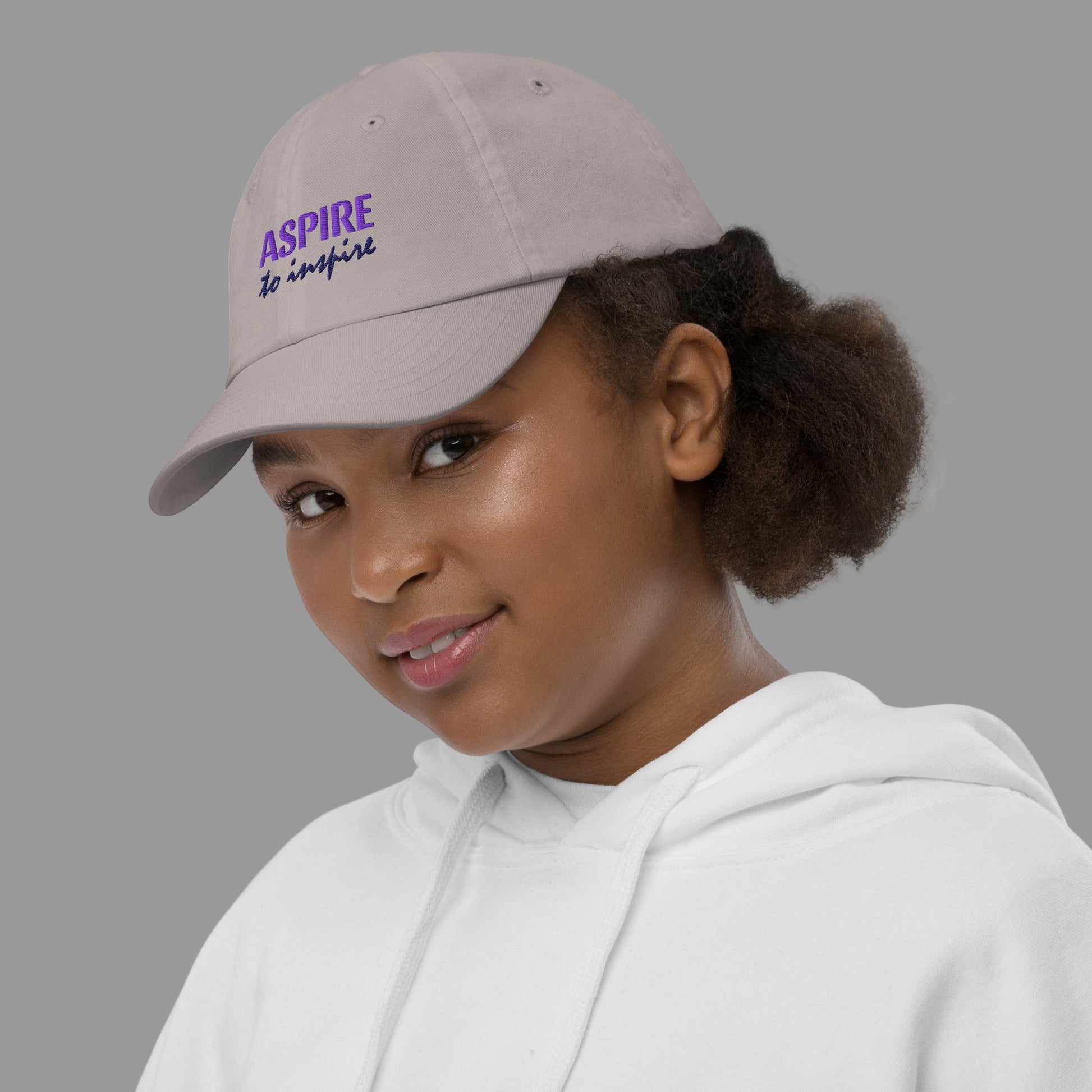 Person wearing a cap with 'Aspire to inspire' text on a white background
