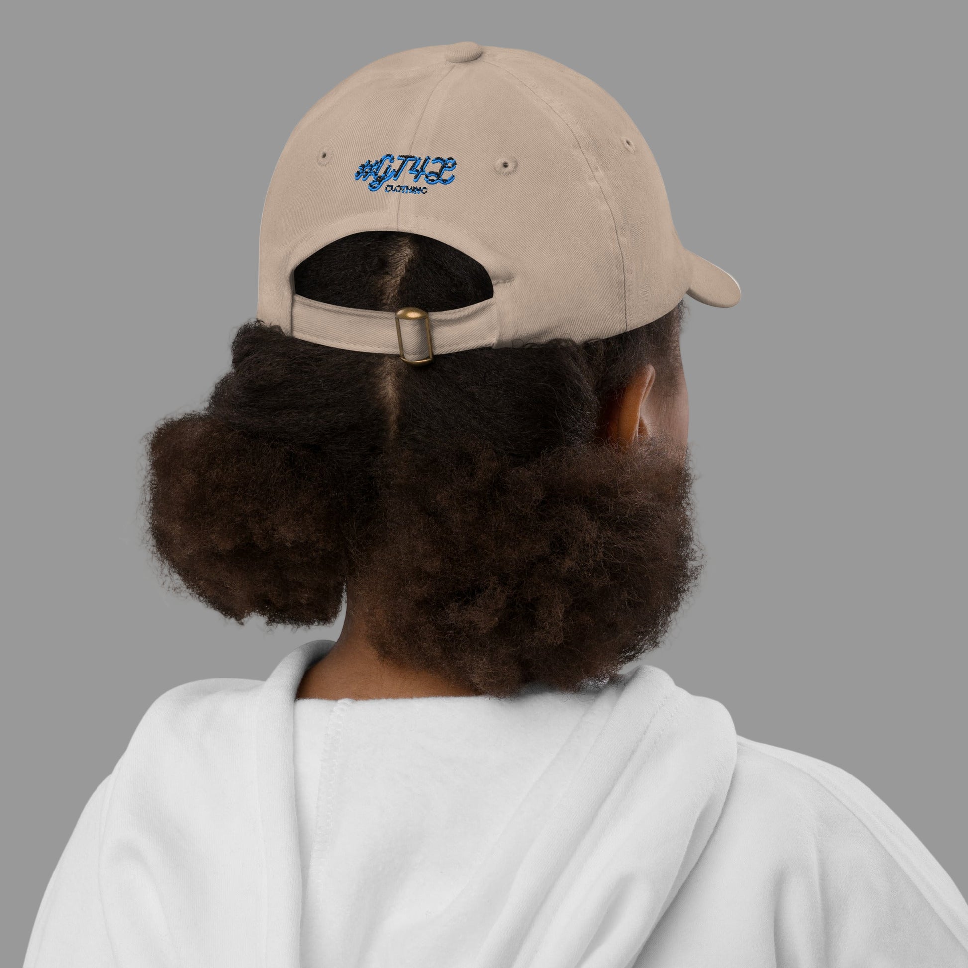 Person wearing a beige cap with a logo on the back, facing away from the camera.