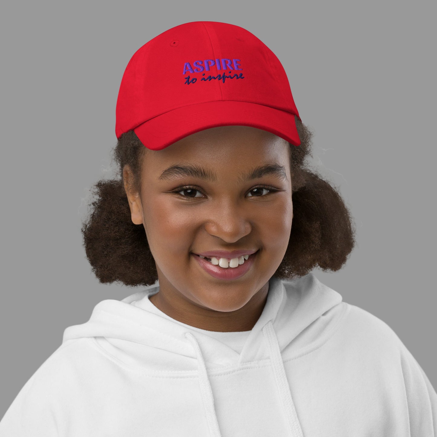 Child wearing a red cap with 'Aspire' text on a white background
