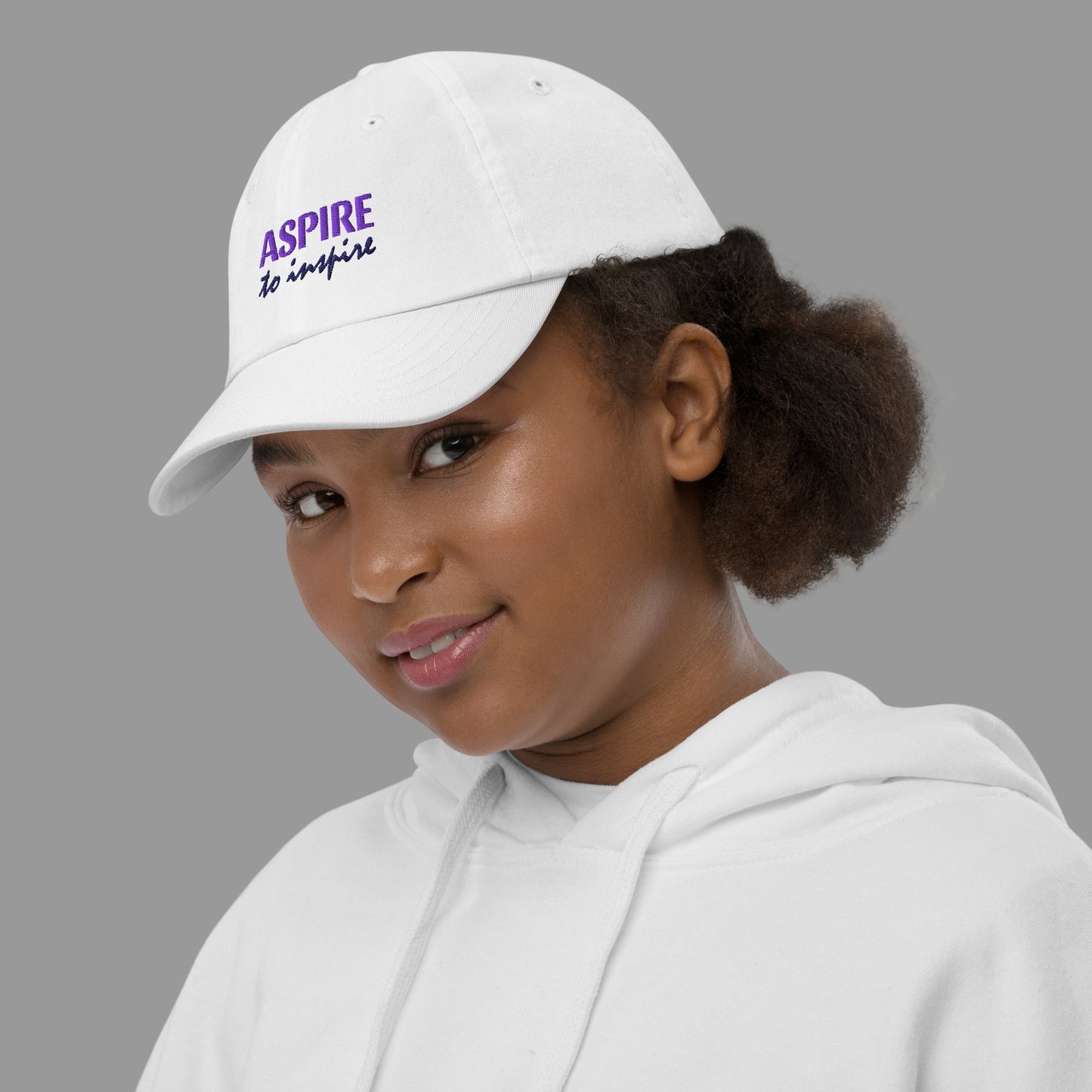 Person wearing a white cap with 'Aspire' text on a white background