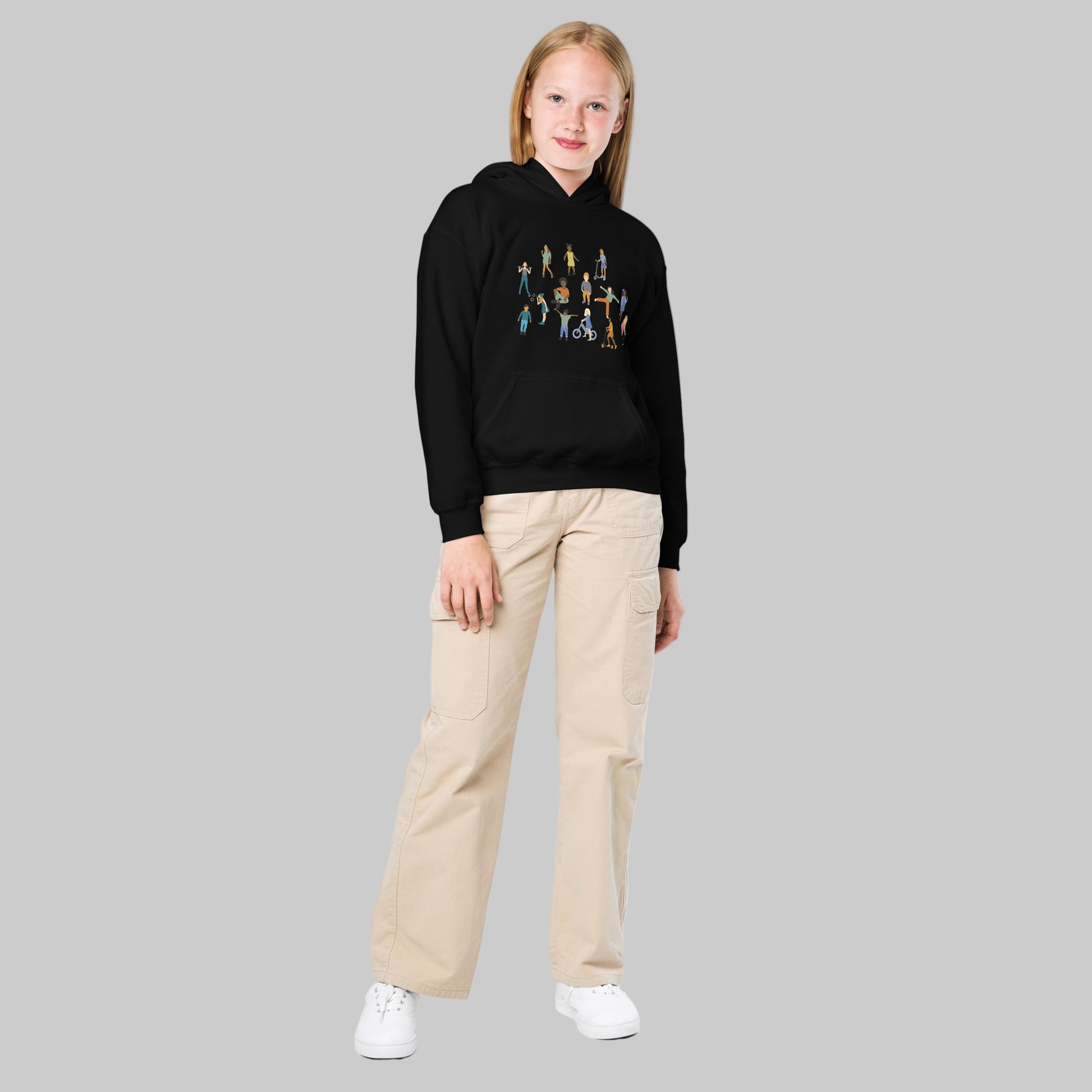 Person wearing a black hoodie with a colorful graphic and beige pants on a white background