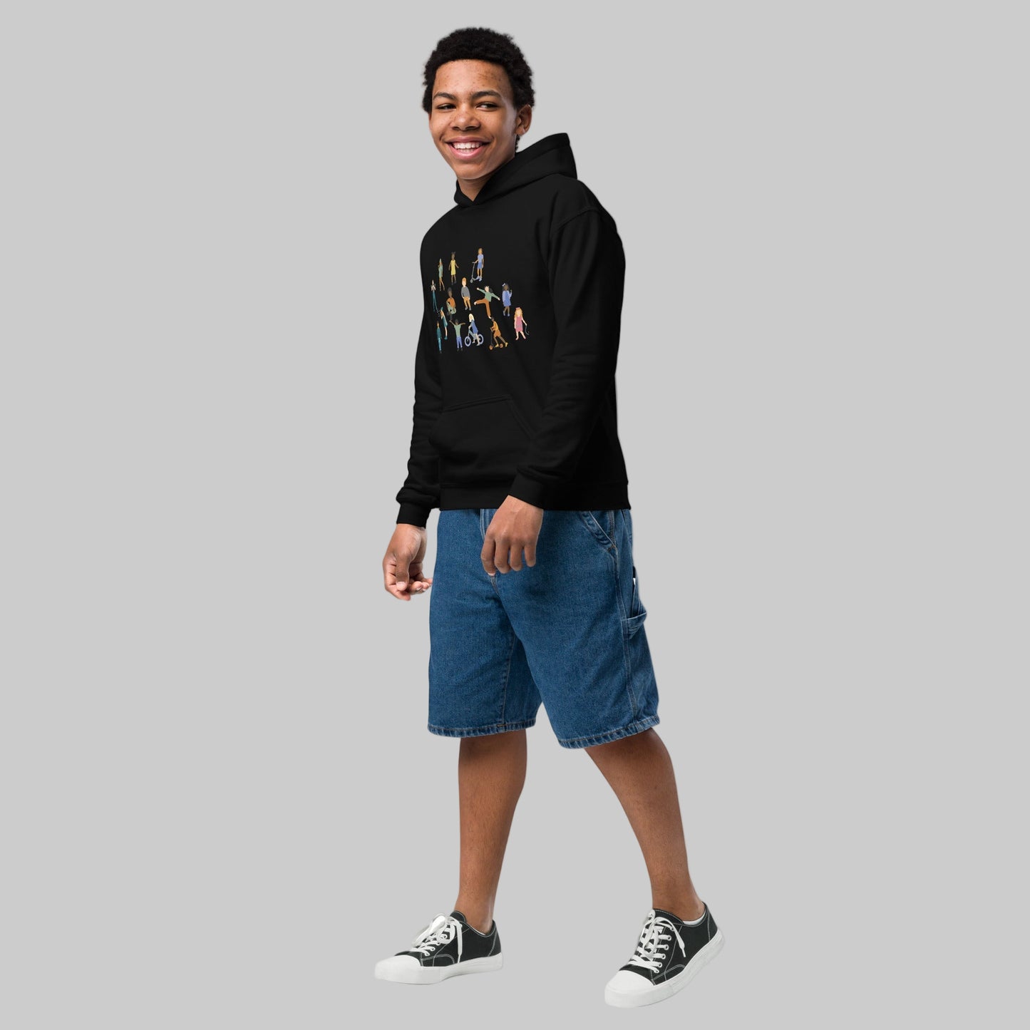 Person wearing a black hoodie with colorful design and blue shorts on a white background